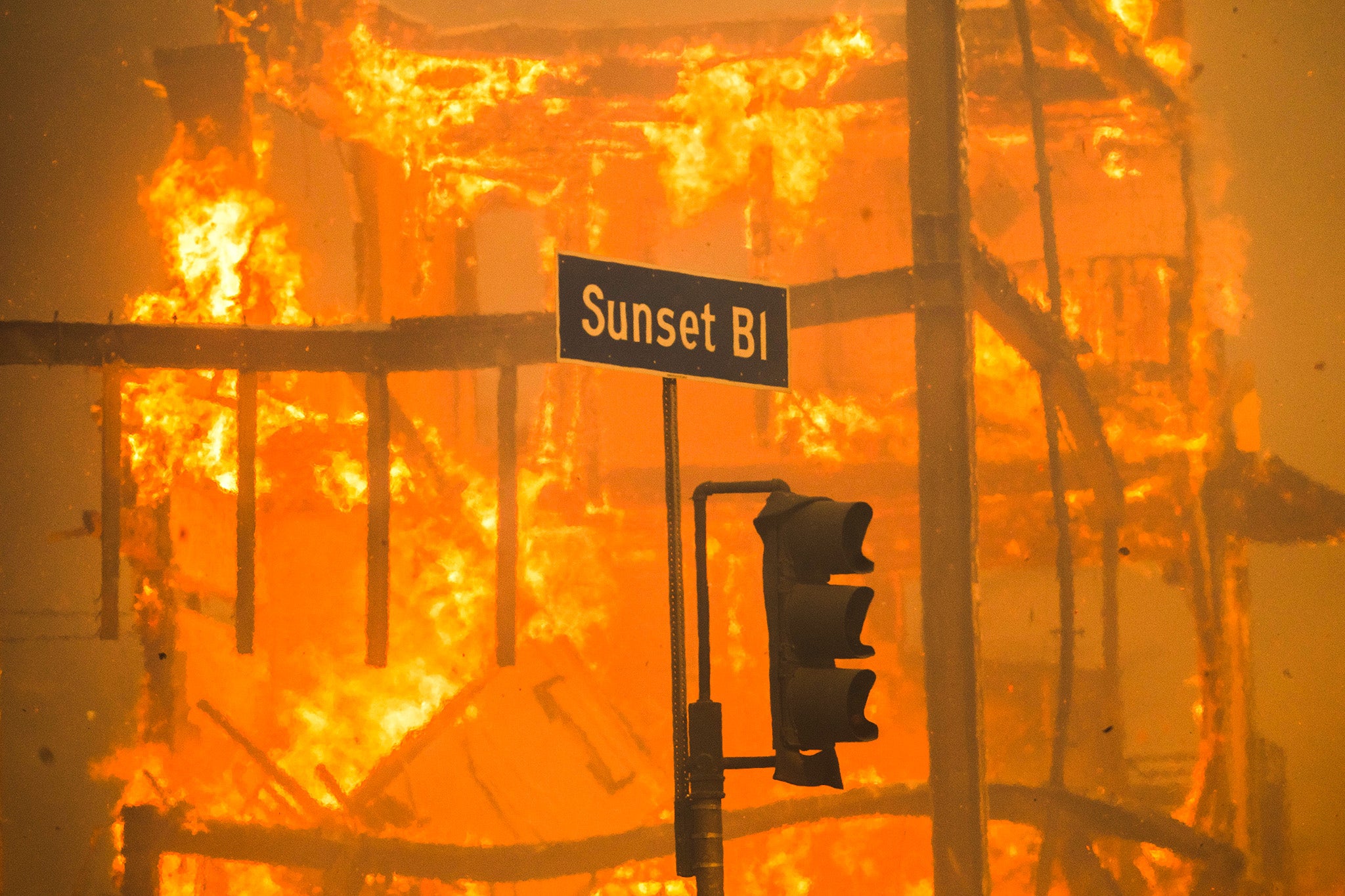 Flames from the Palisades Fire burn a building on Sunset Boulevard