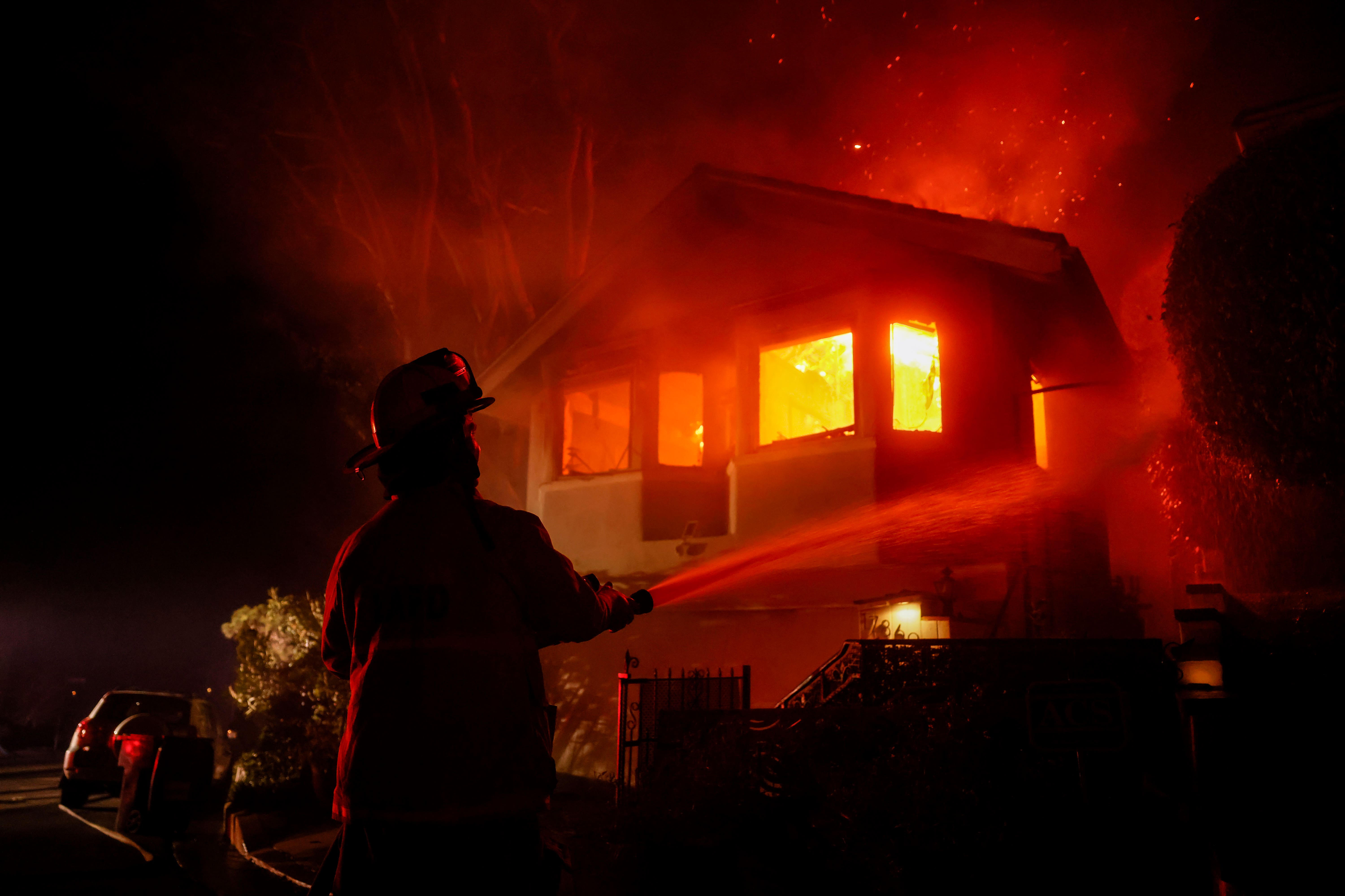 A firefighter, pictured, as a Palisades Fire burns a house in the hill next to the Getty Villa (AP Photo/Etienne Laurent)