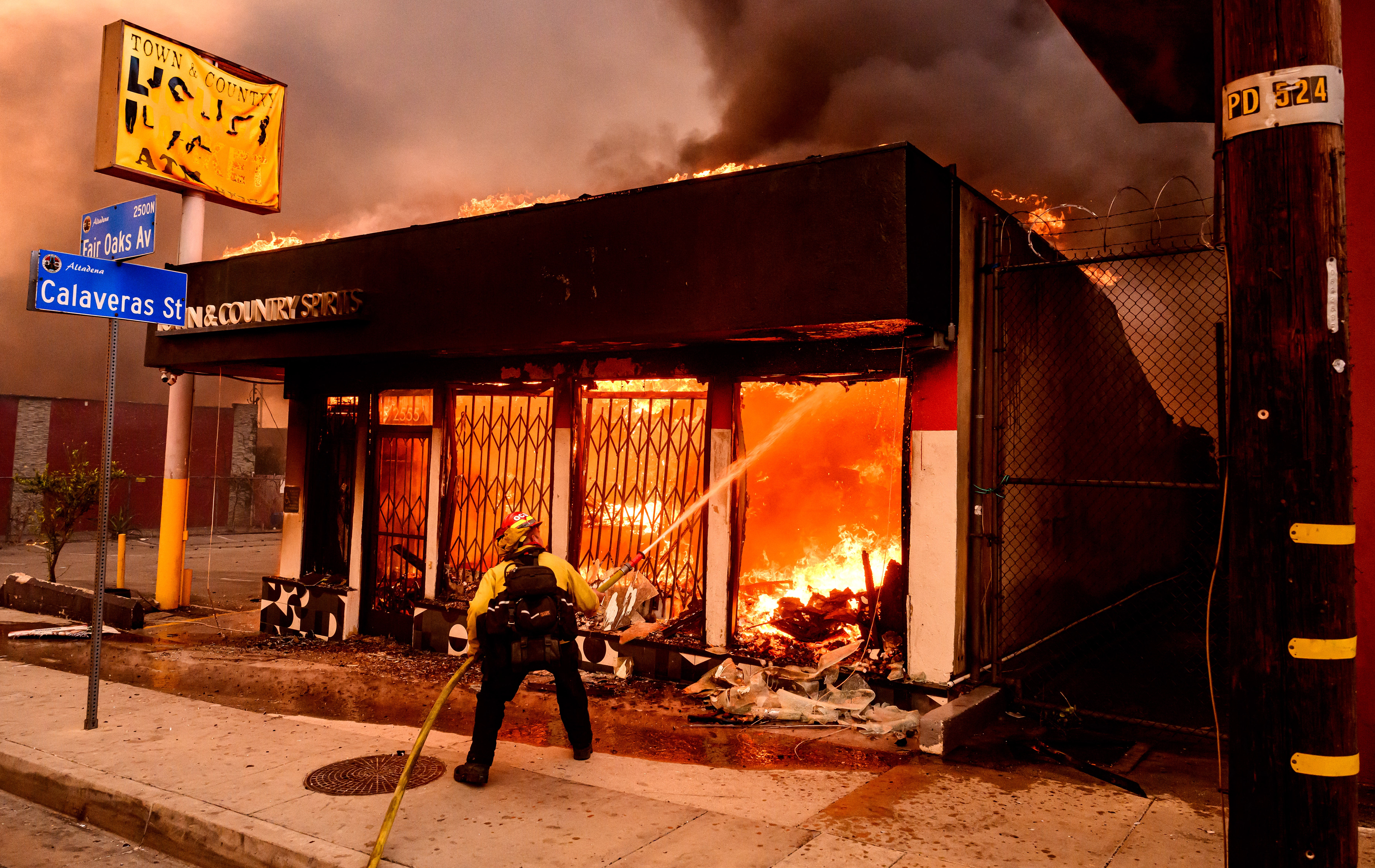 A firefighter douses flames as a liquor store burns during the Eaton fire