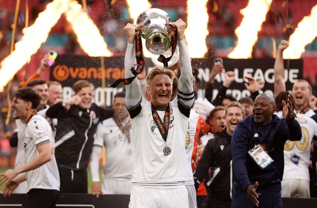 <p>Captain Byron Webster celebrates with the trophy after Bromley’s play-off victory in May</p>
