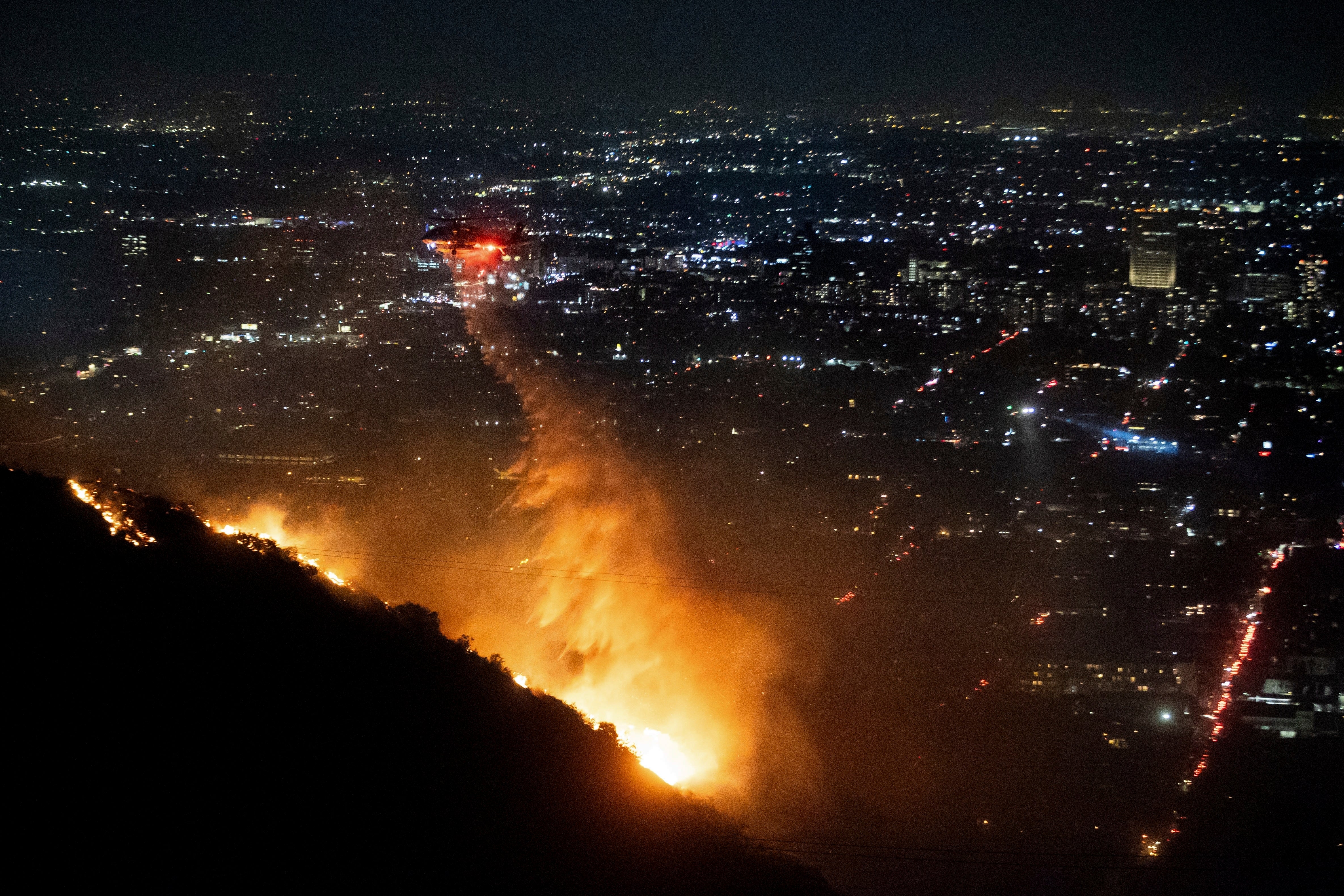 Water is dropped by helicopter on the burning Sunset Fire in the Hollywood Hills section of Los Angeles, Wednesday, January 8 2025