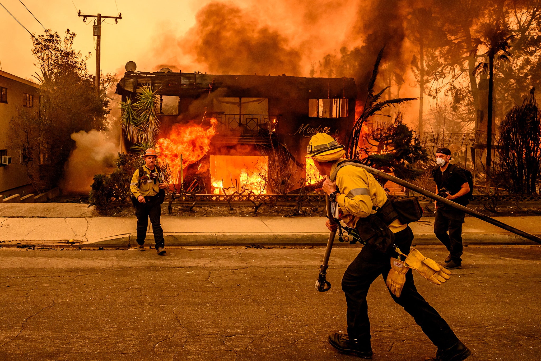 Firefighters working to extinguish flames engulfing a building during the Eaton fire in the Altadena area