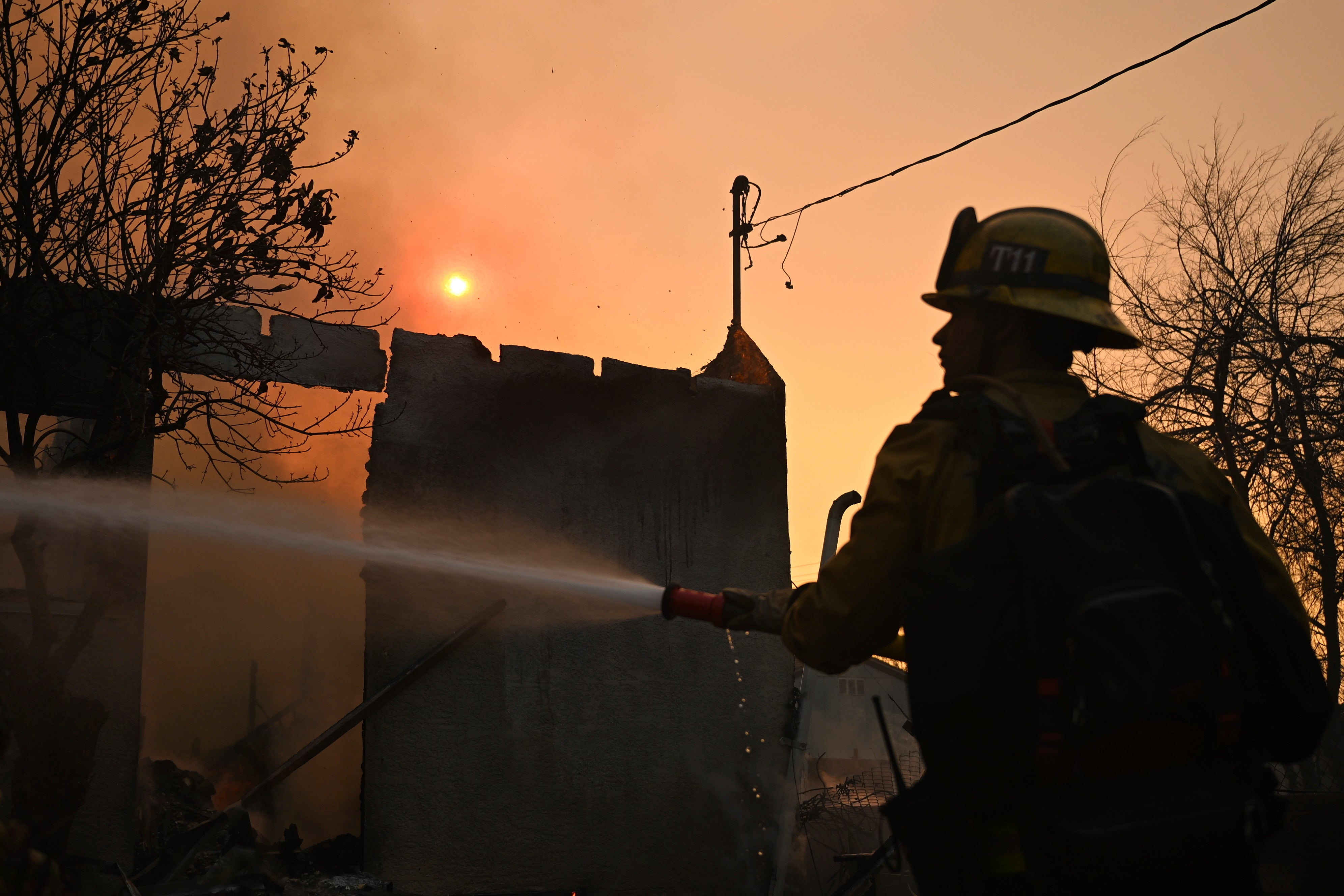 A firefighter waters down a home after the Eaton Fire in Altadena, California., on Thursday. The fire remained 0 percent contained