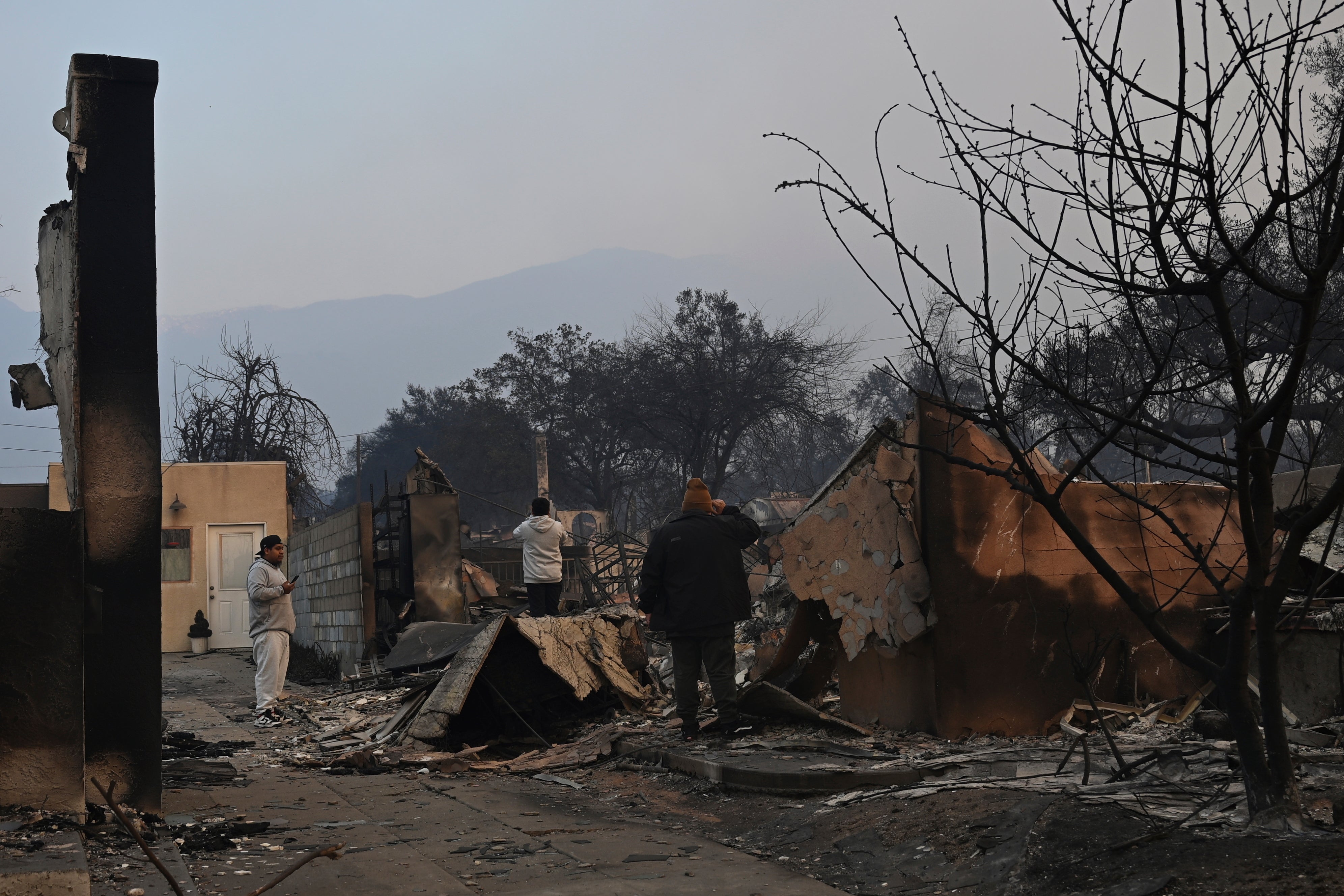 People look over damaged structures on Thursday following the Eaton Fire in Altadena, California. The blaze resulted in several deaths and more injuries