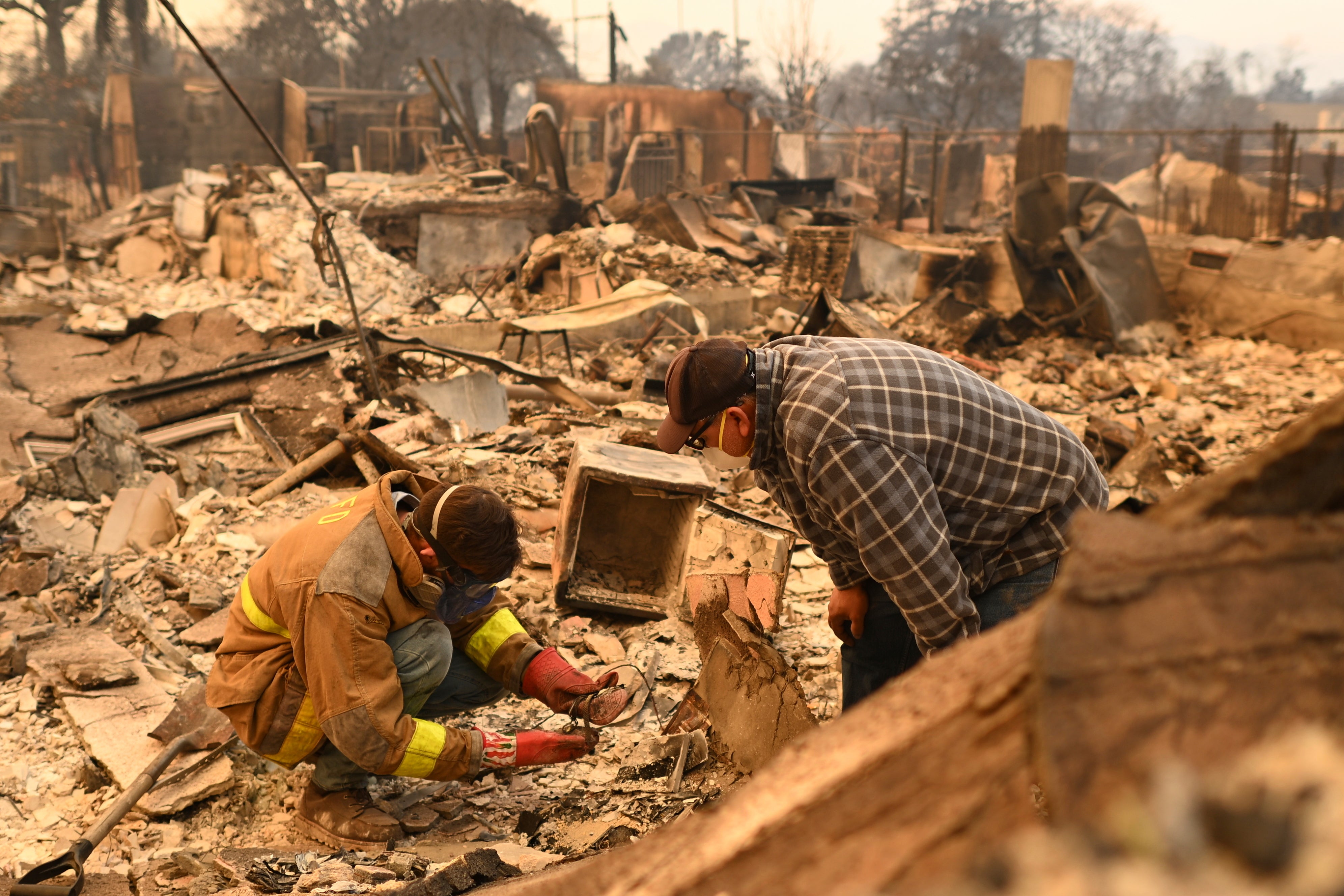 Robert Lara, left, looks for belongings along with his stepfather on Thursday following the Eaton Fire in Altadena, California. Windy conditions were not over