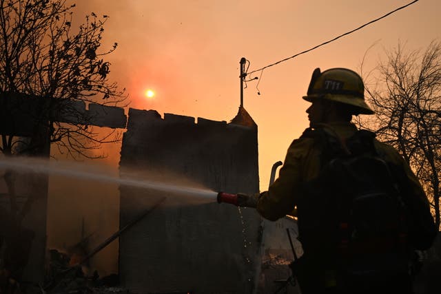 <p>A firefighter waters down a home after the Eaton Fire burns in Altadena, California. Some have questioned if ocean water can be used to battle the blazes </p>