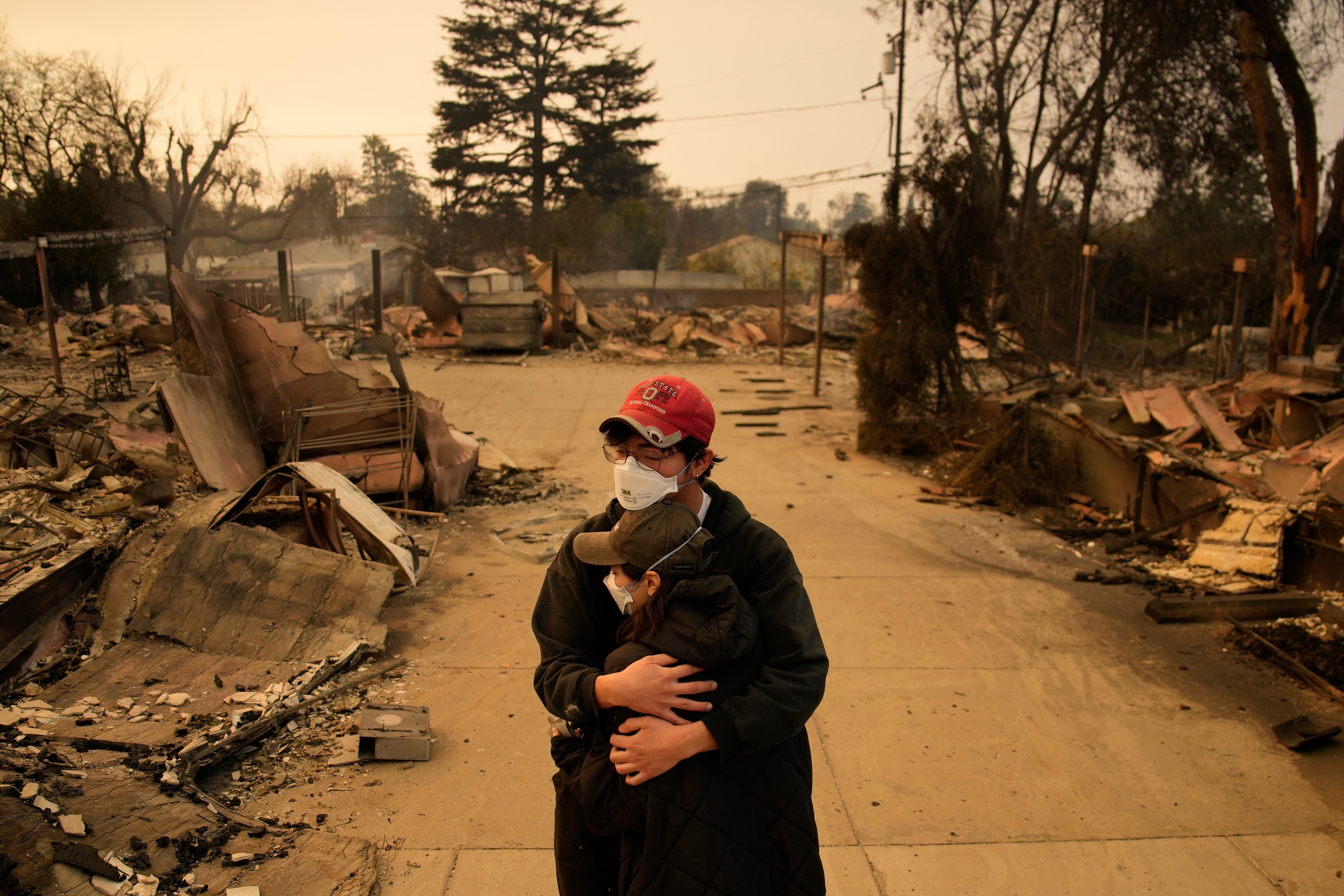 A man and woman hold each other in the rubble of destroyed homes in Altadena, California, on Thursday.