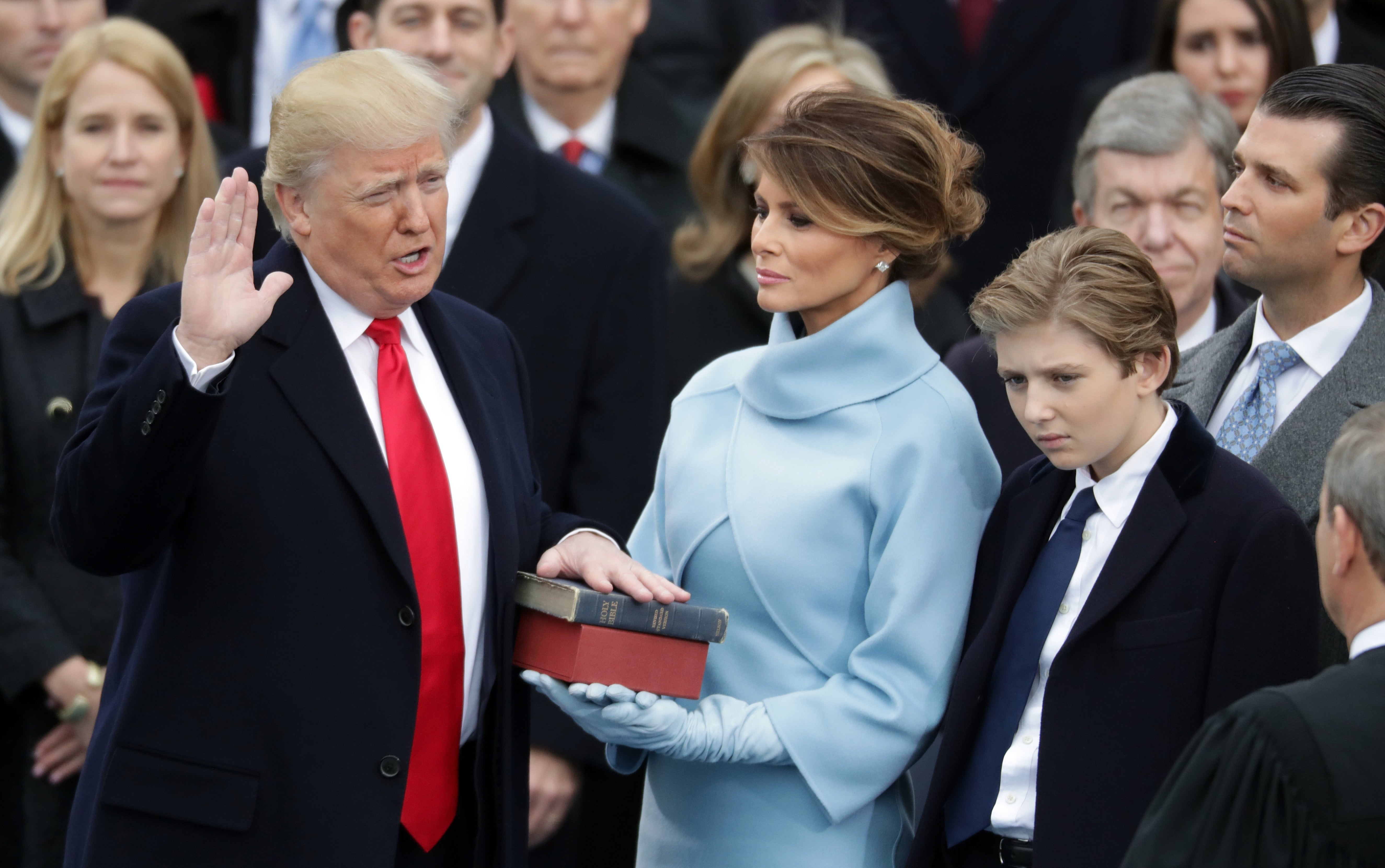 Trump pictured taking the oath of office in 2017 as his wife Melania and his son Barron watch on