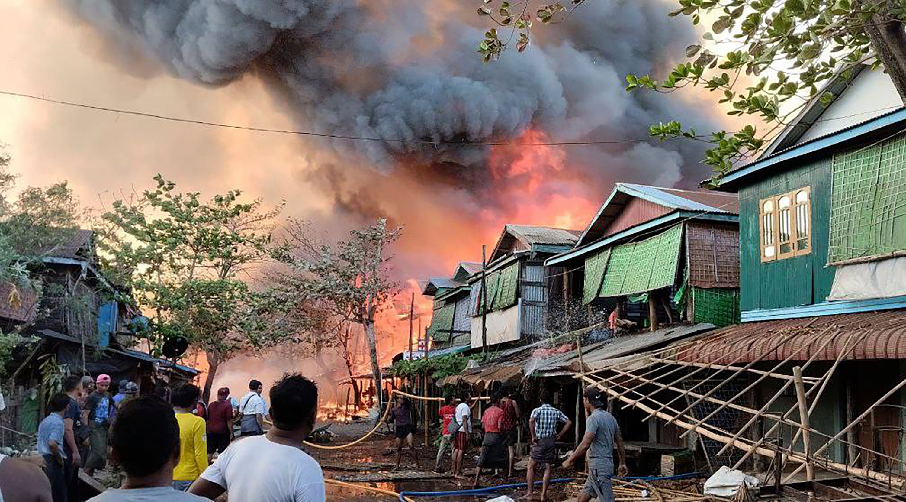 <p>People douse flames after an airstrike by the military in Kyauk Ni Maw village of Ramree township in Rakhine state, Myanmar, on Wednesday</p>