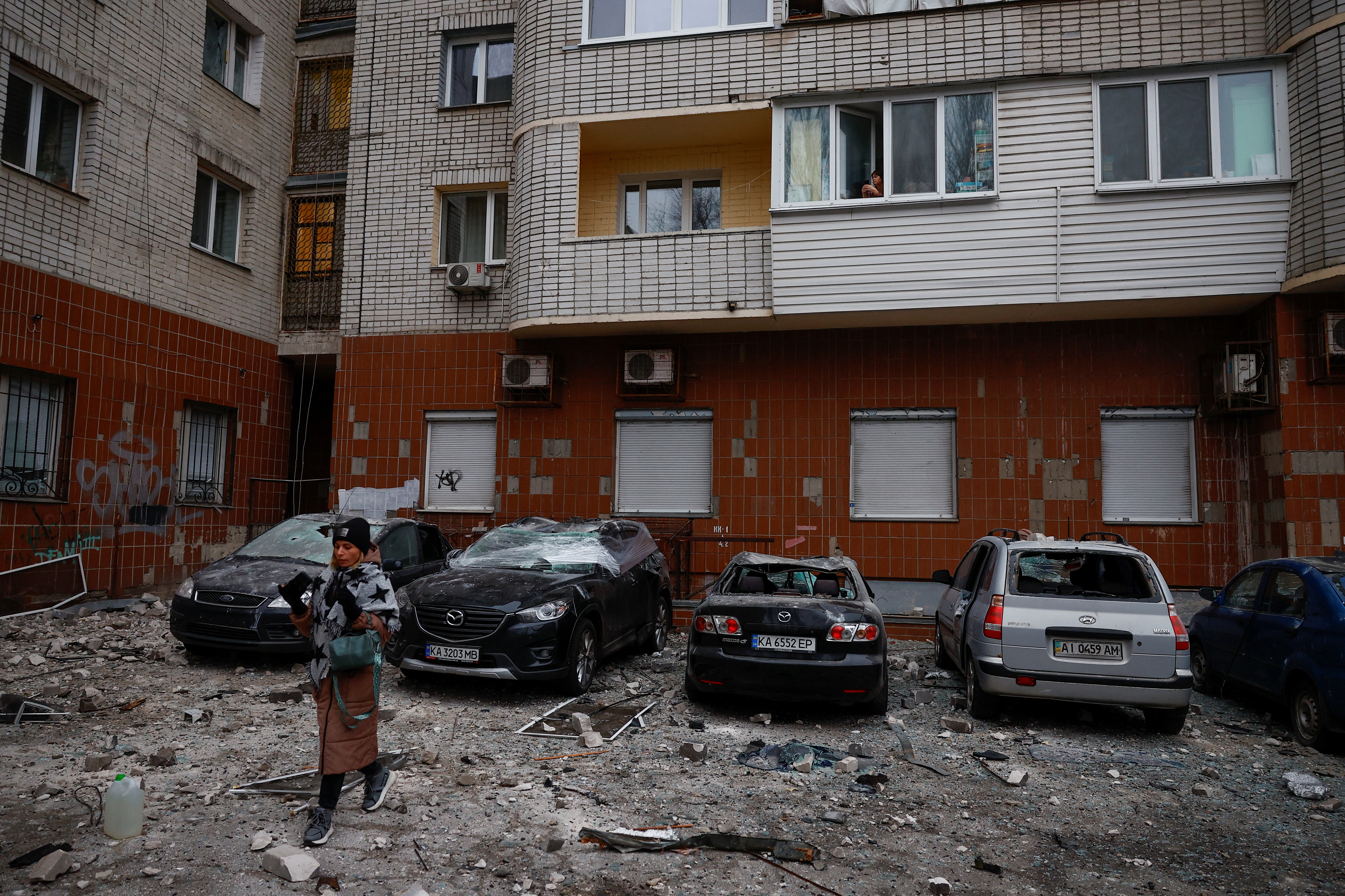 A resident walks next to cars damaged during a Russian drone strike, amid Russia's attack on Ukraine