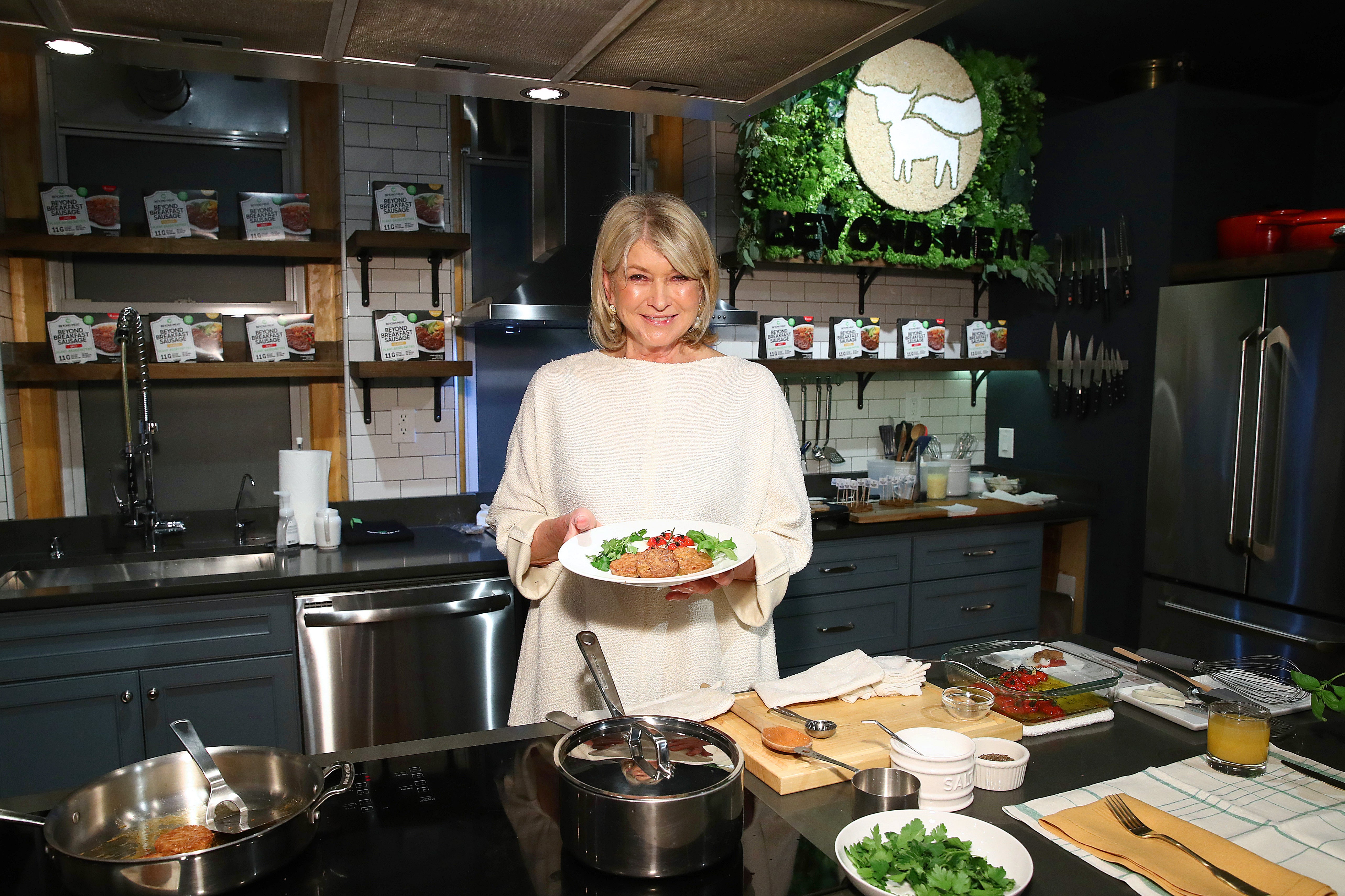 Martha Stewart with a plate of plant-based sausages and roast tomatoes