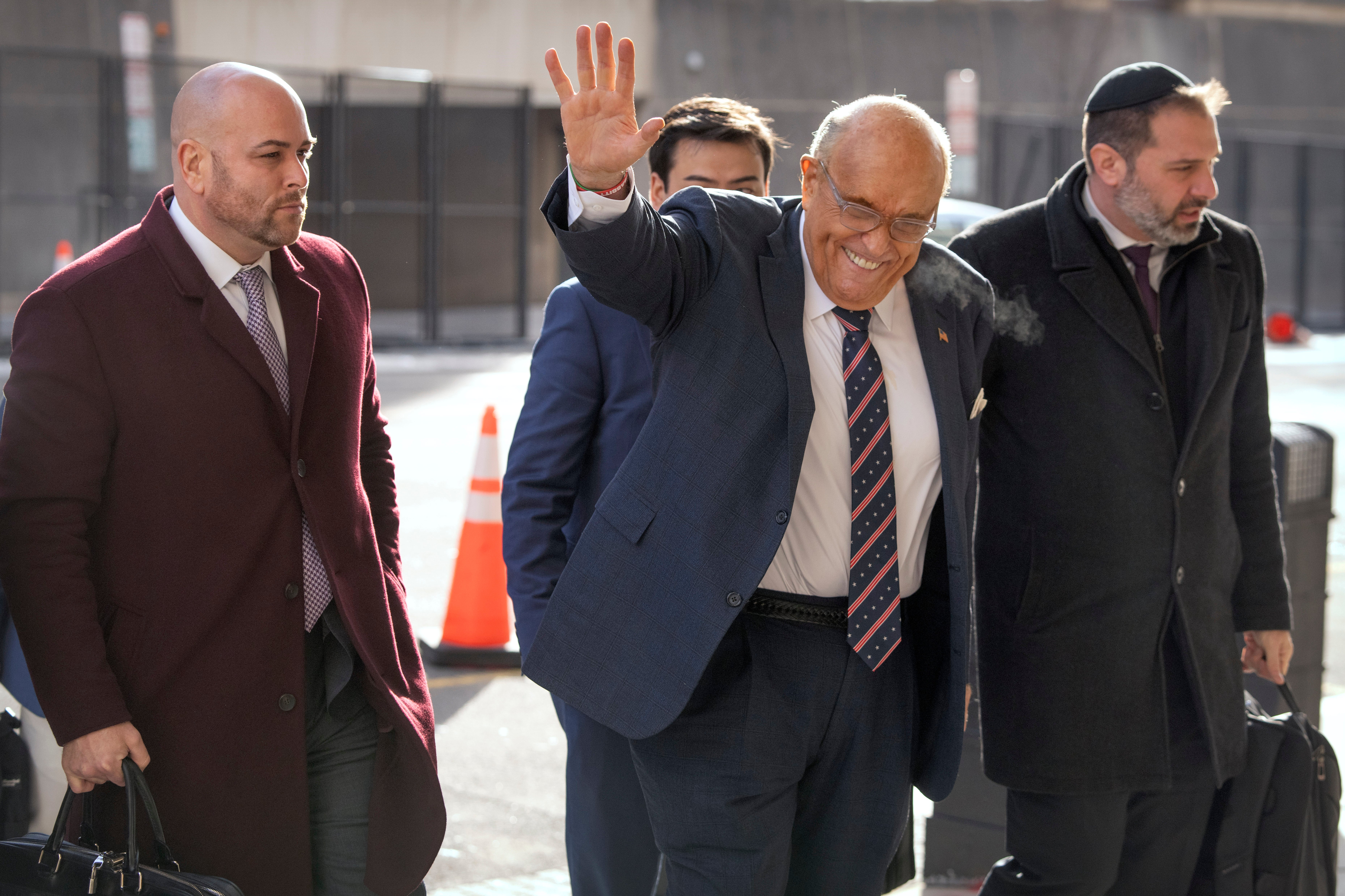 Rudy Giuliani, second from right, waves as he arrives at federal court in Washington