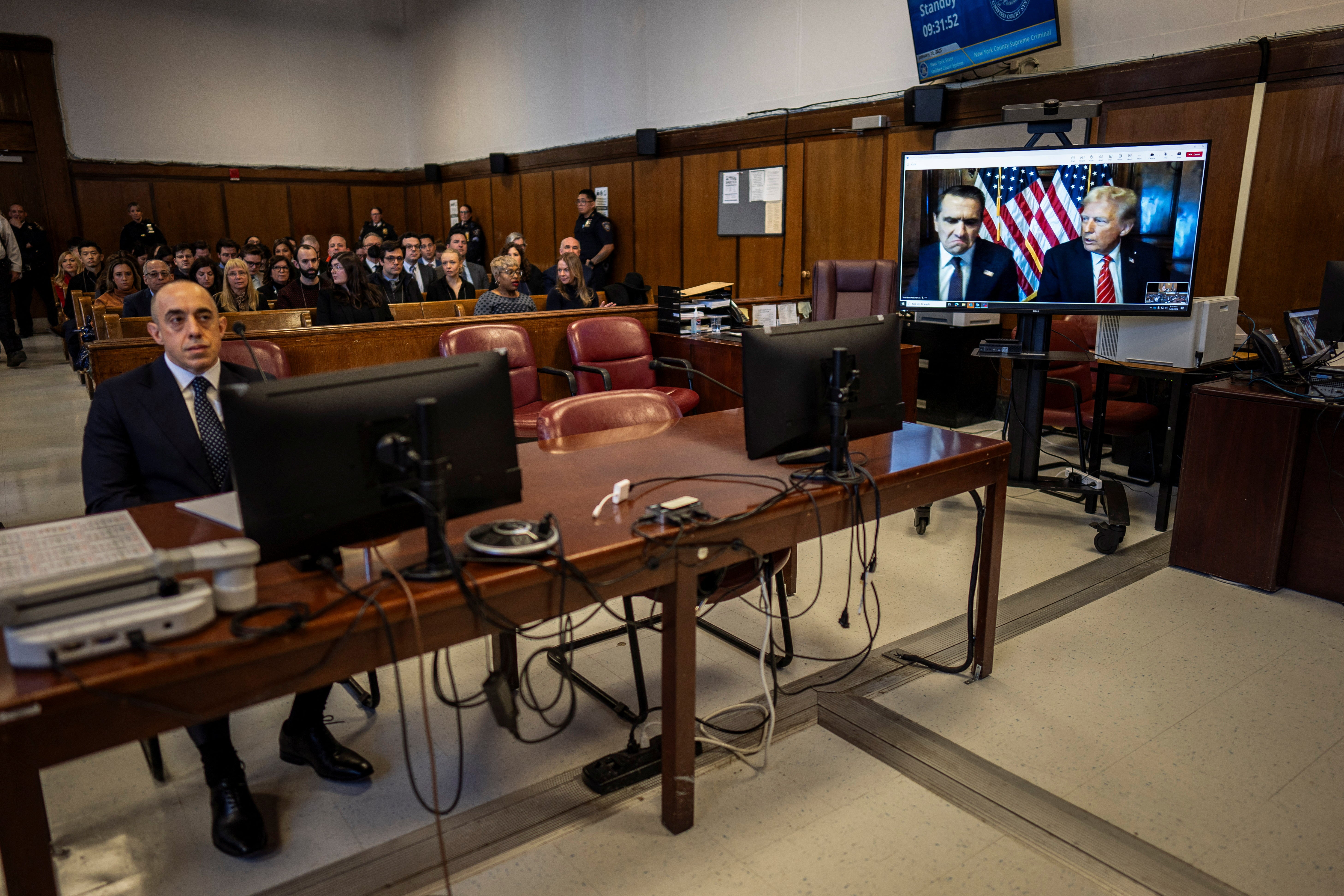 Attorney Emil Bove, left, listens as Attorney Todd Blanche and President-elect Trump, seen on a television screen, appear virtually for sentencing