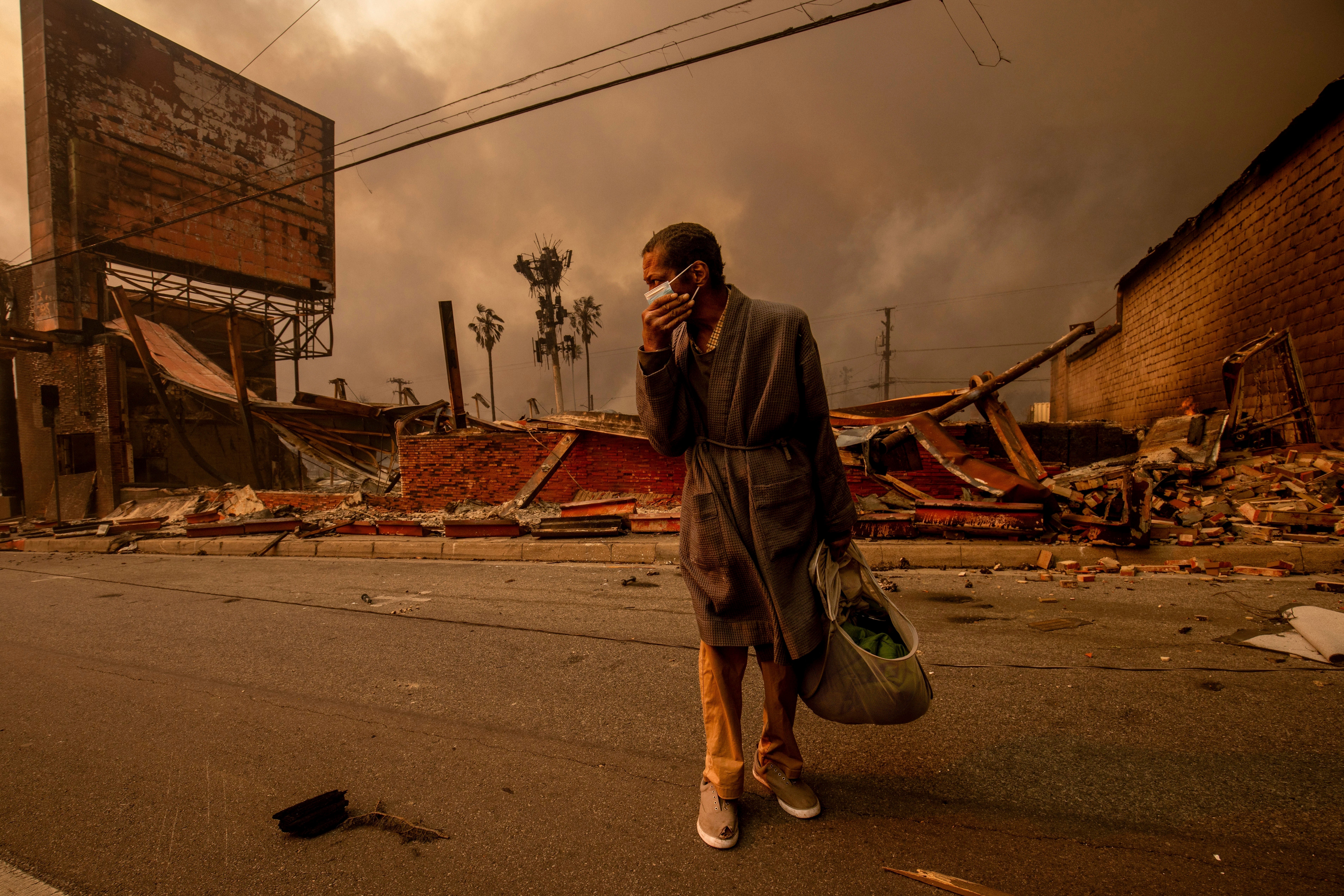 A man walks past a fire-ravaged business after the Eaton Fire on Wednesday in Altadena, California. Devastating and deadly wildfires tore through and flattened communities this week, fanned by dangerous Santa Ana winds