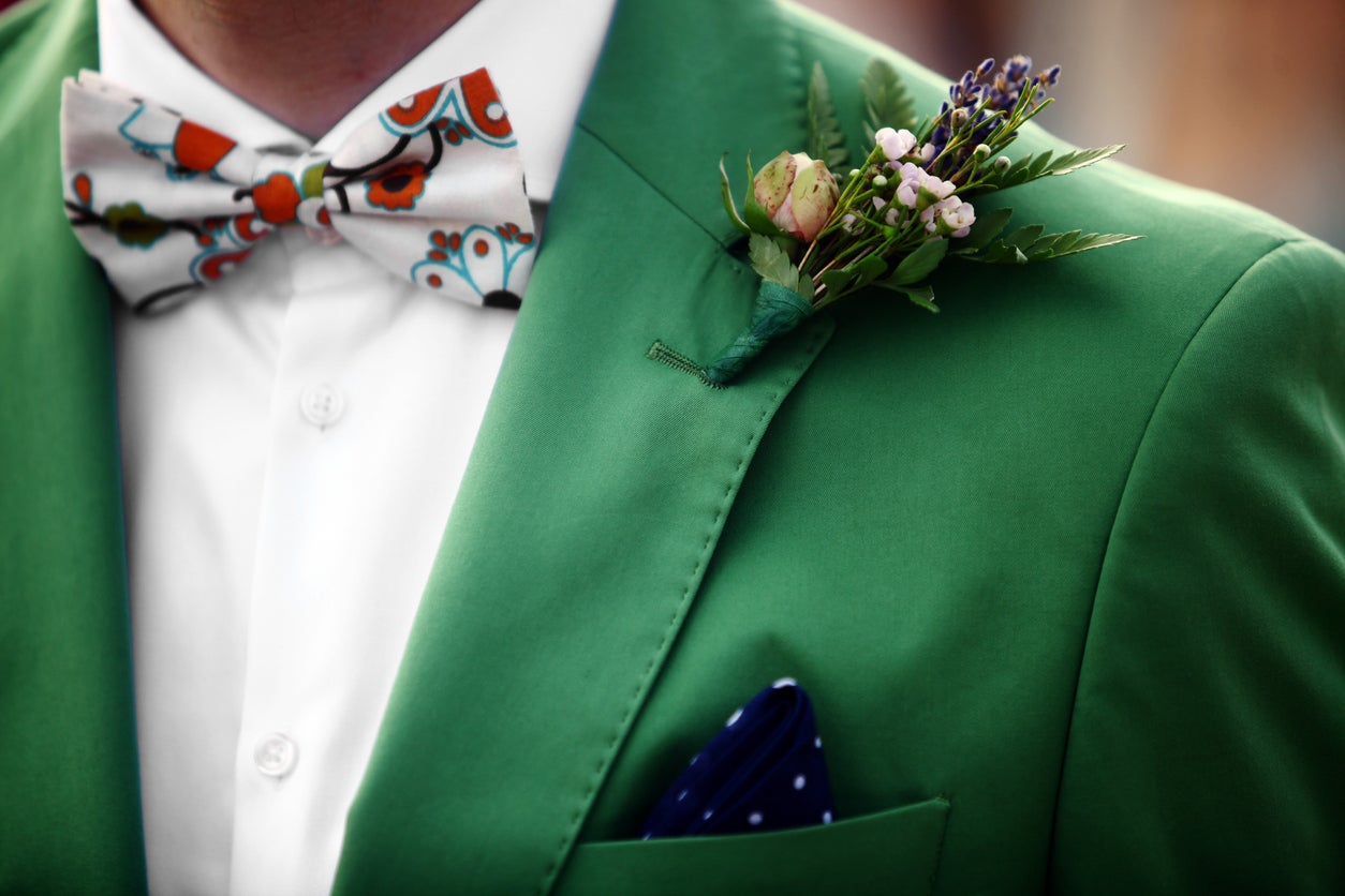 A groom wearing a colorful green jacket and bowtie