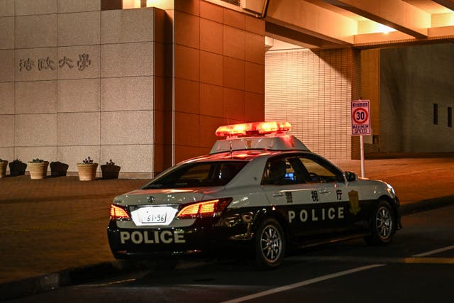 <p>A police car sits at the entrance to Hosei University’s Tama campus where eight people were wounded in a hammer attack </p>