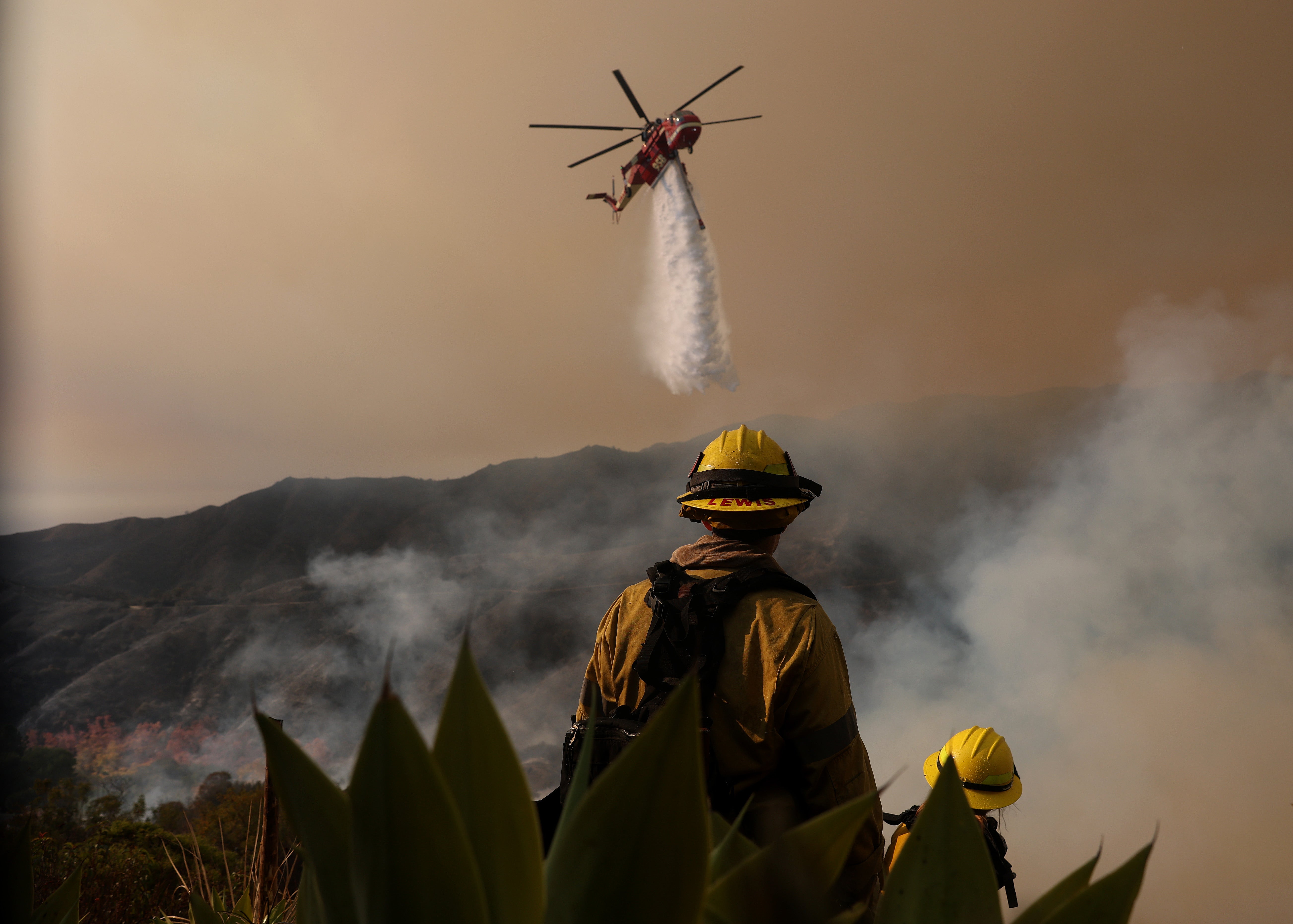 A firefighting helicopter drops water on the Palisades fire on January 10