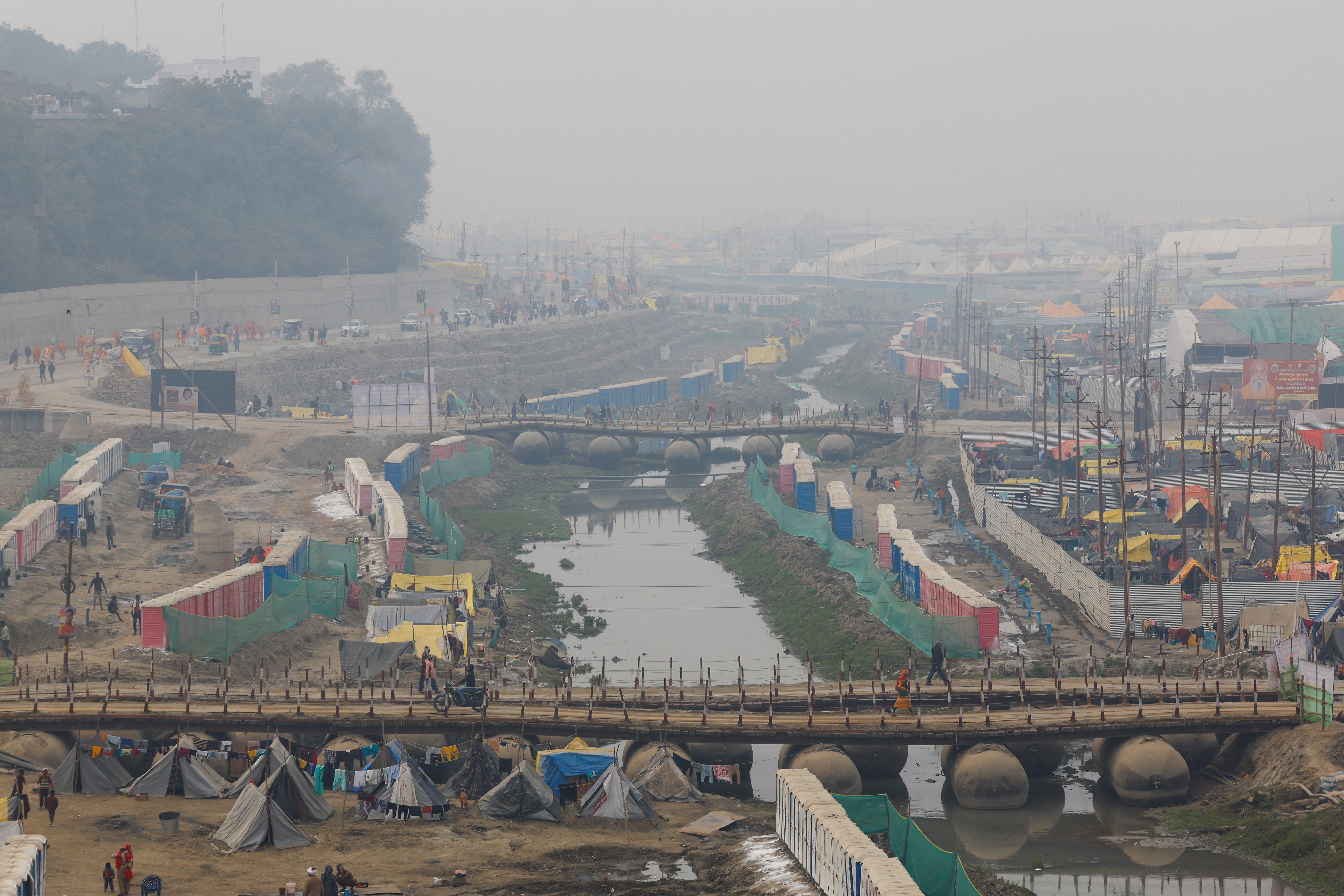 Hindu devotees cross a pontoon bridge spanning the river Ganga as they arrive to attend the Maha Kumbh Mela