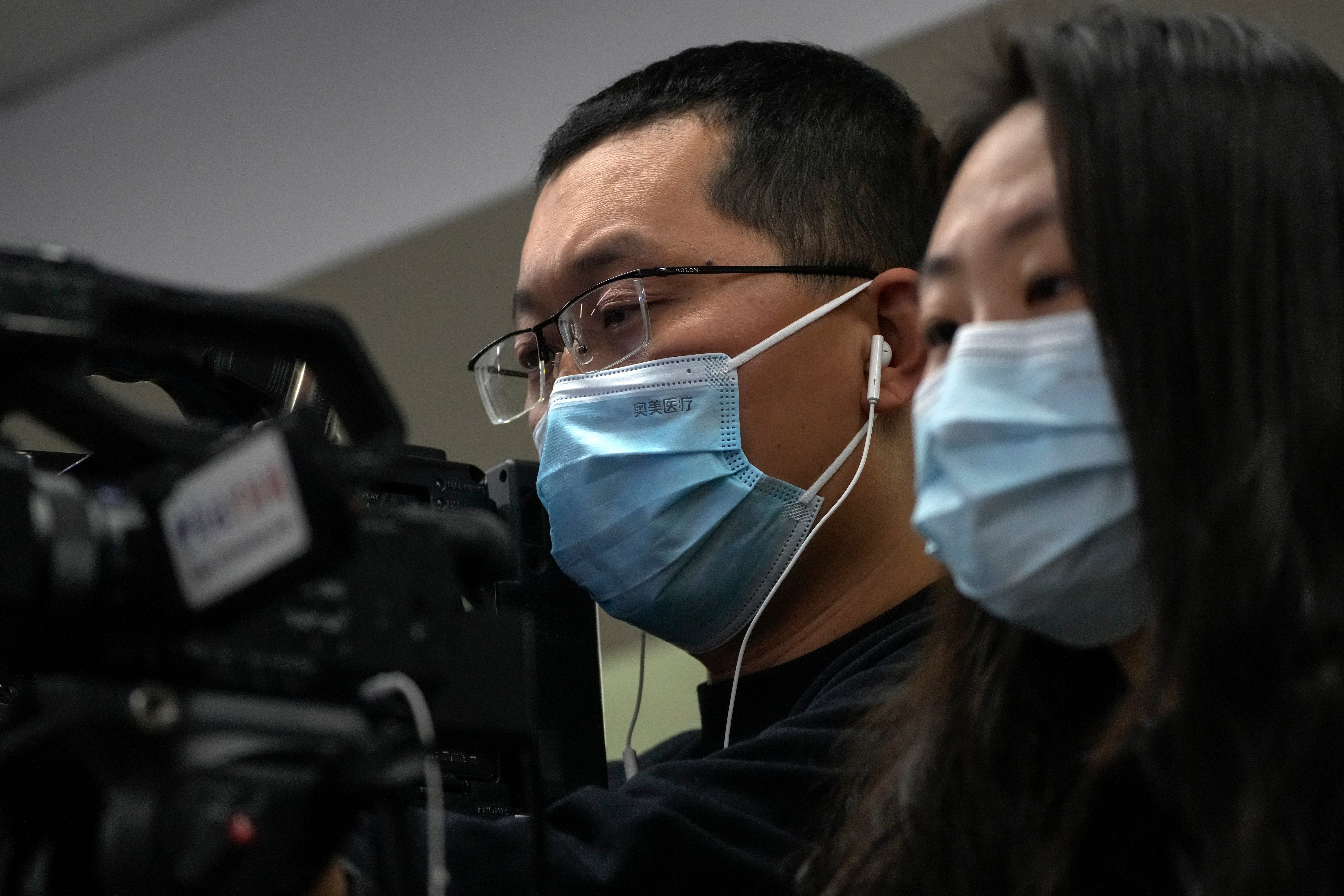 Journalists wearing face masks film a speech of Wang Liping, a researcher for the Chinese Center for Disease Control and Prevention during a press briefing by the National Health Commission in Beijing, Sunday, Jan. 12