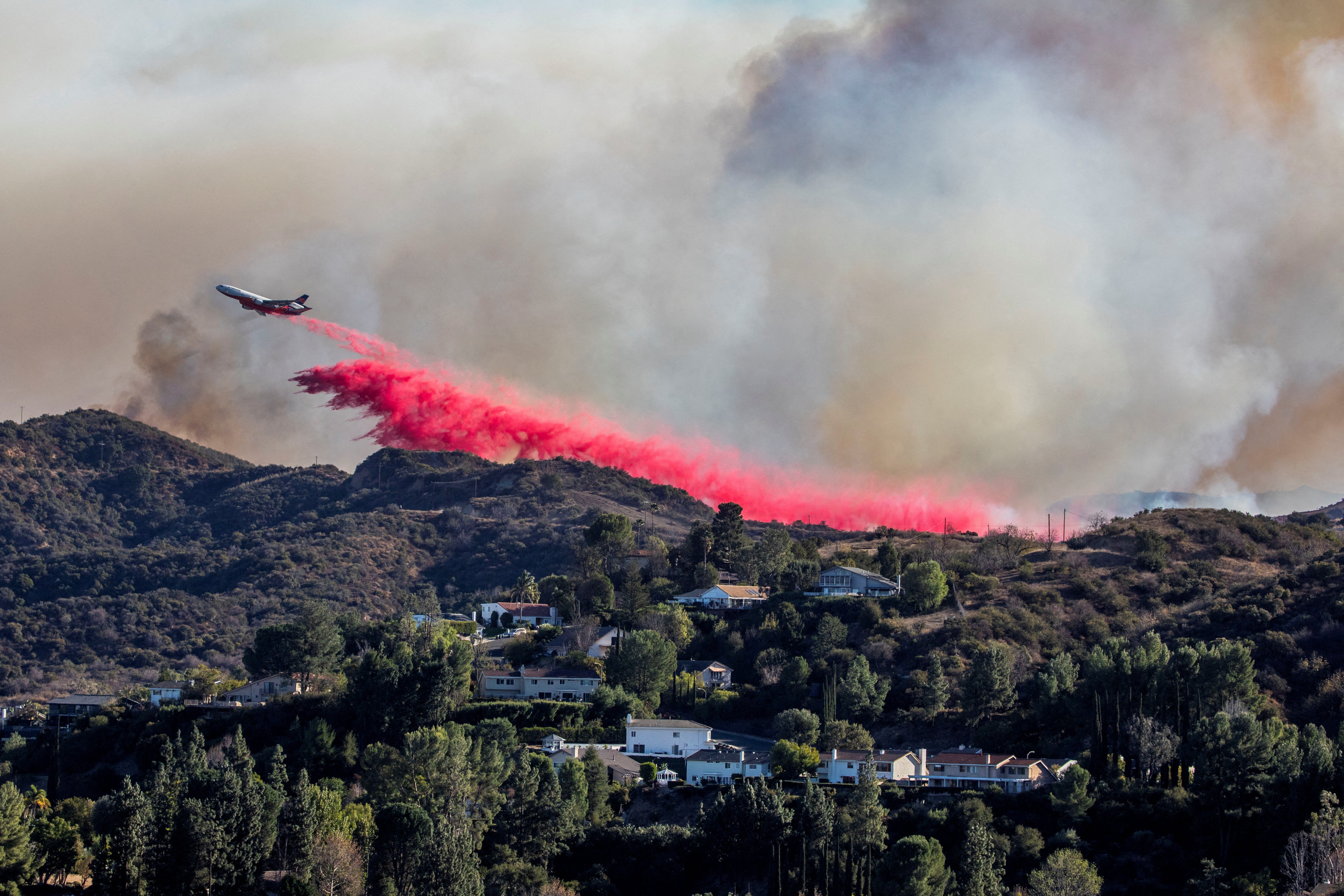 <p>An air tanker drops fire retardant at the Palisades fire, one of the simultaneous blazes that have ripped across Los Angeles County</p>