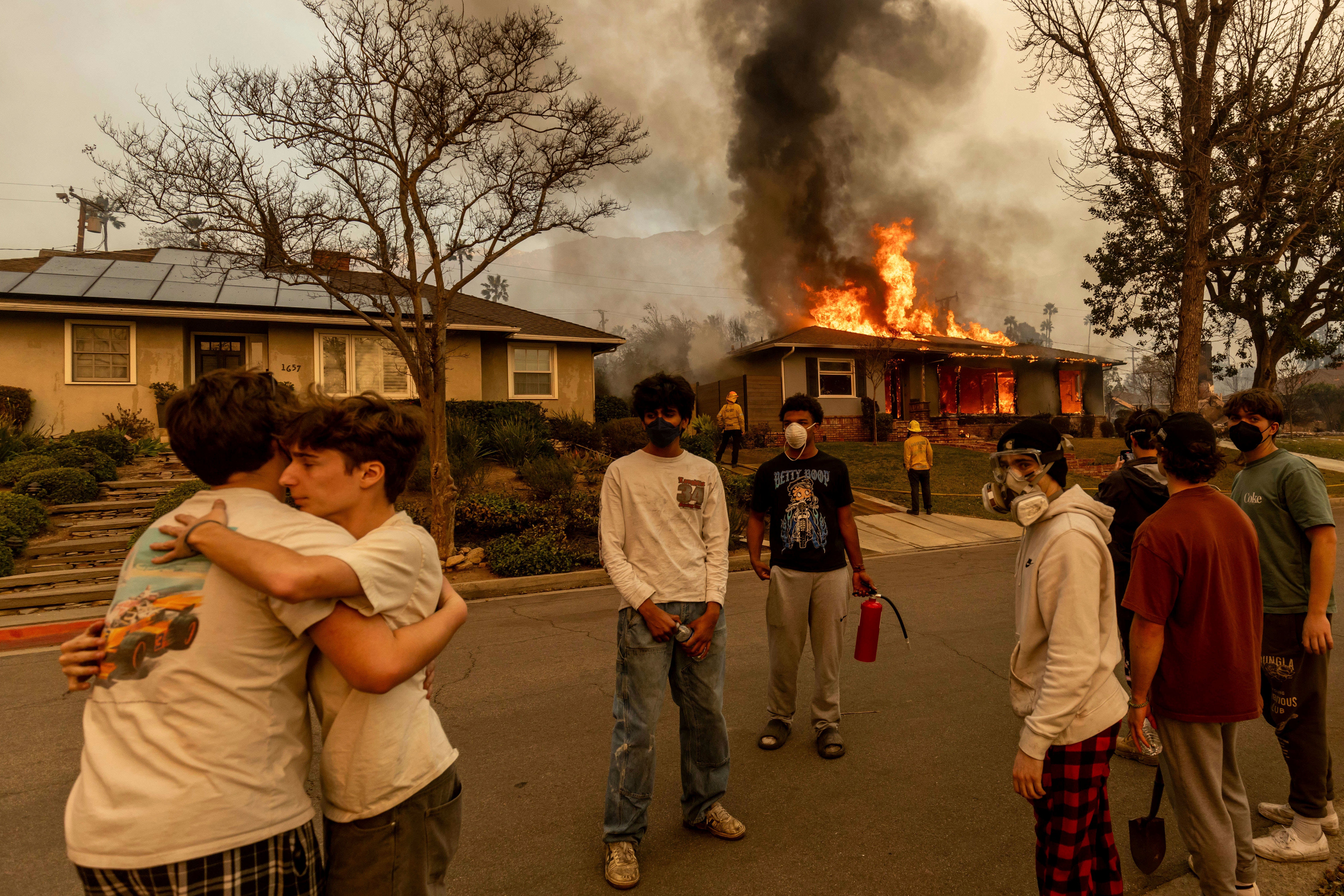 Residents embrace outside of a burning property as the Eaton fire swept through Altadena on January 8