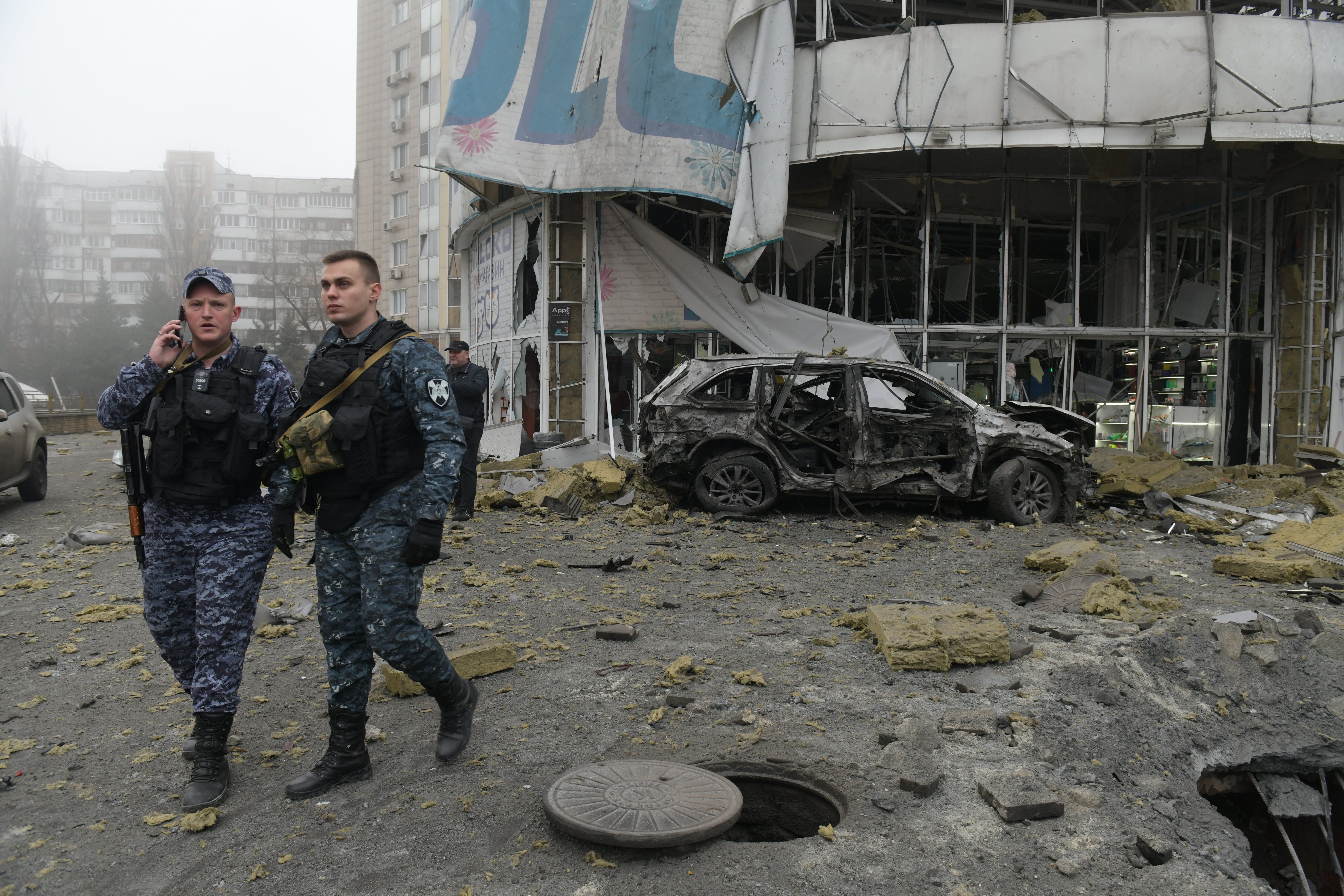 Law enforcement officers walk near a damaged store following shelling in Donetsk, Russian-controlled Ukraine