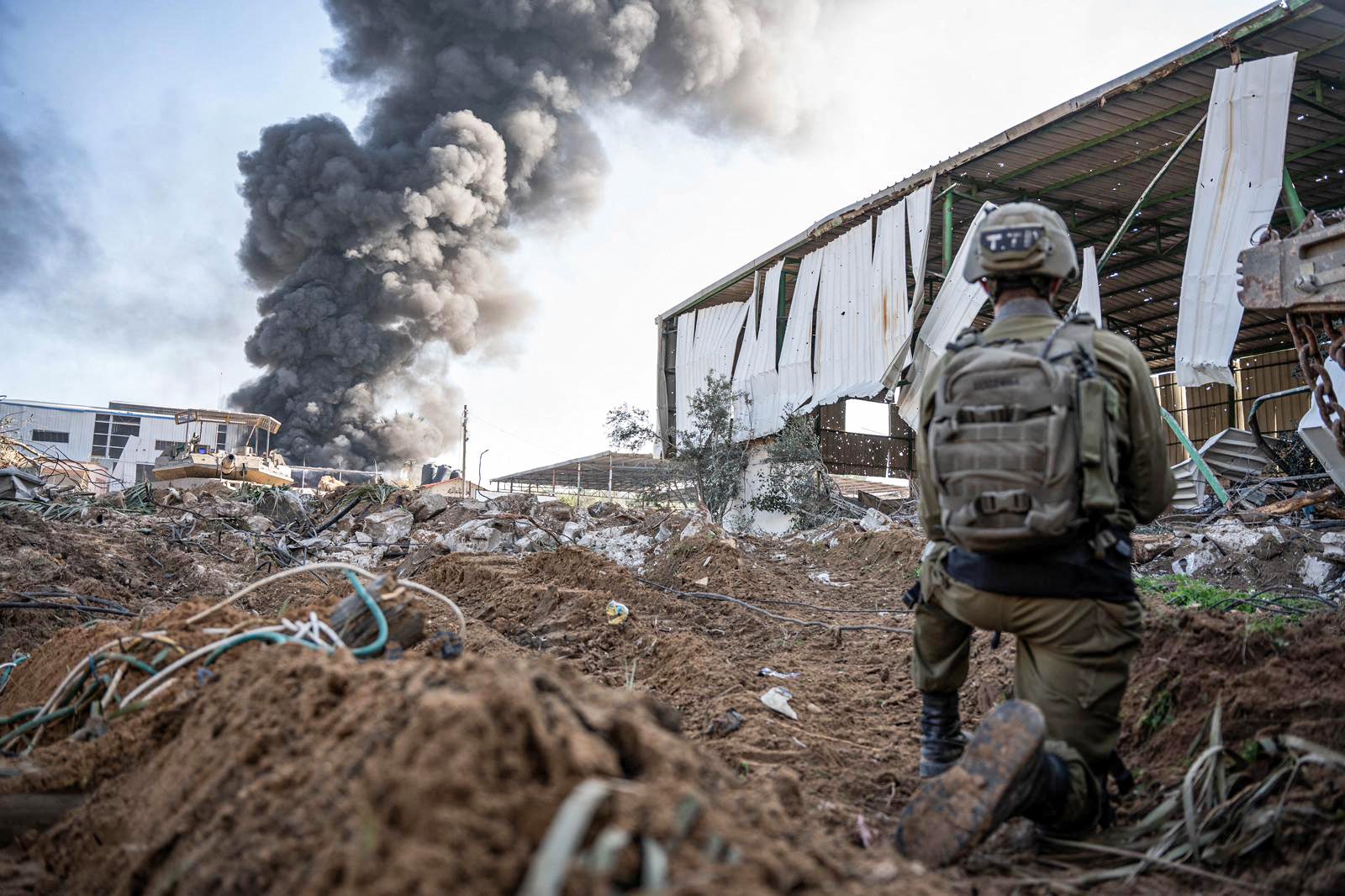 An Israeli soldier as smoke billows in the Gaza Strip