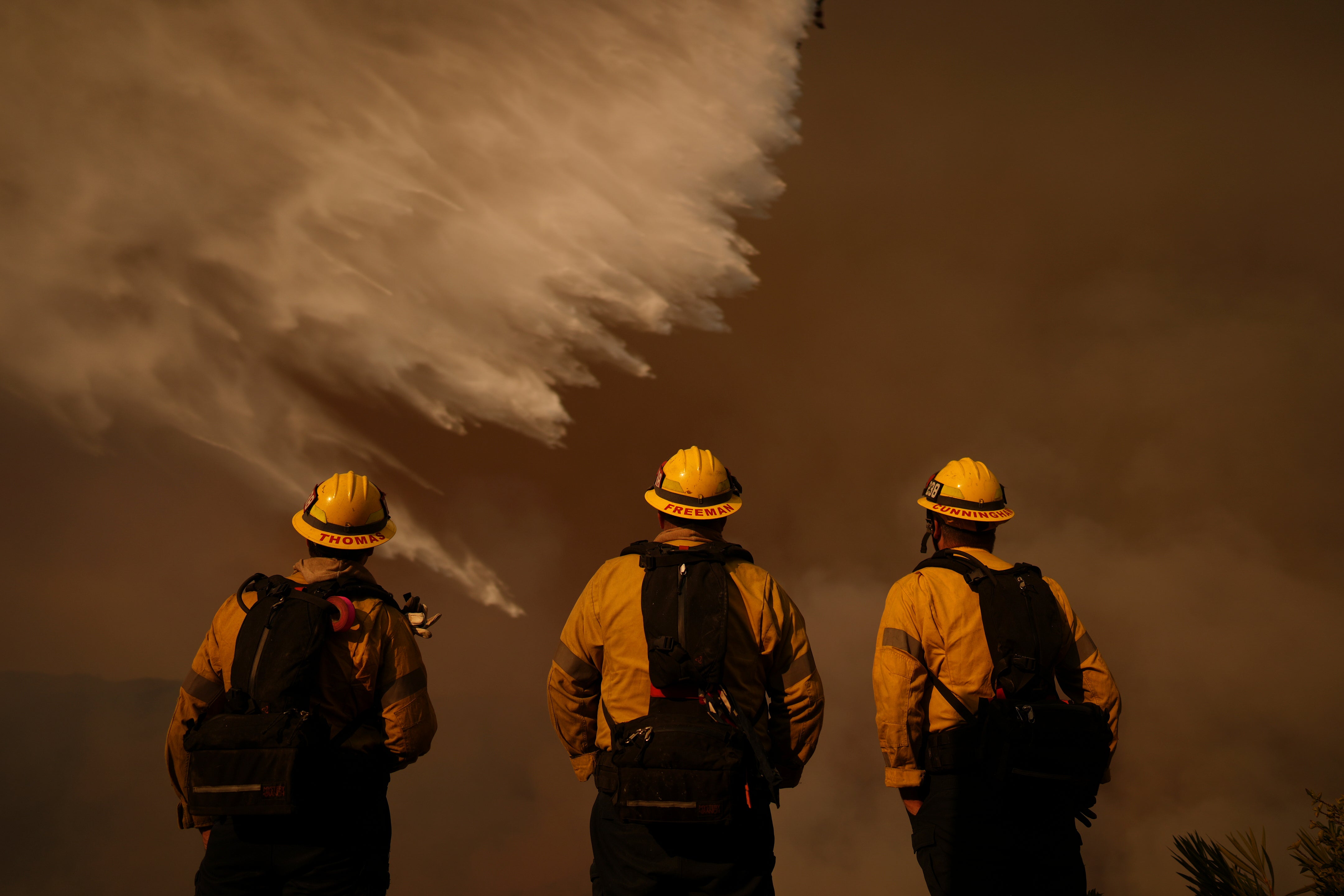 Firefighters watch water drops on the Palisades Fire in Mandeville Canyon on Saturday in Los Angeles, California. Winds were expected to pick up again on Monday after a calm weekend allowed for progress