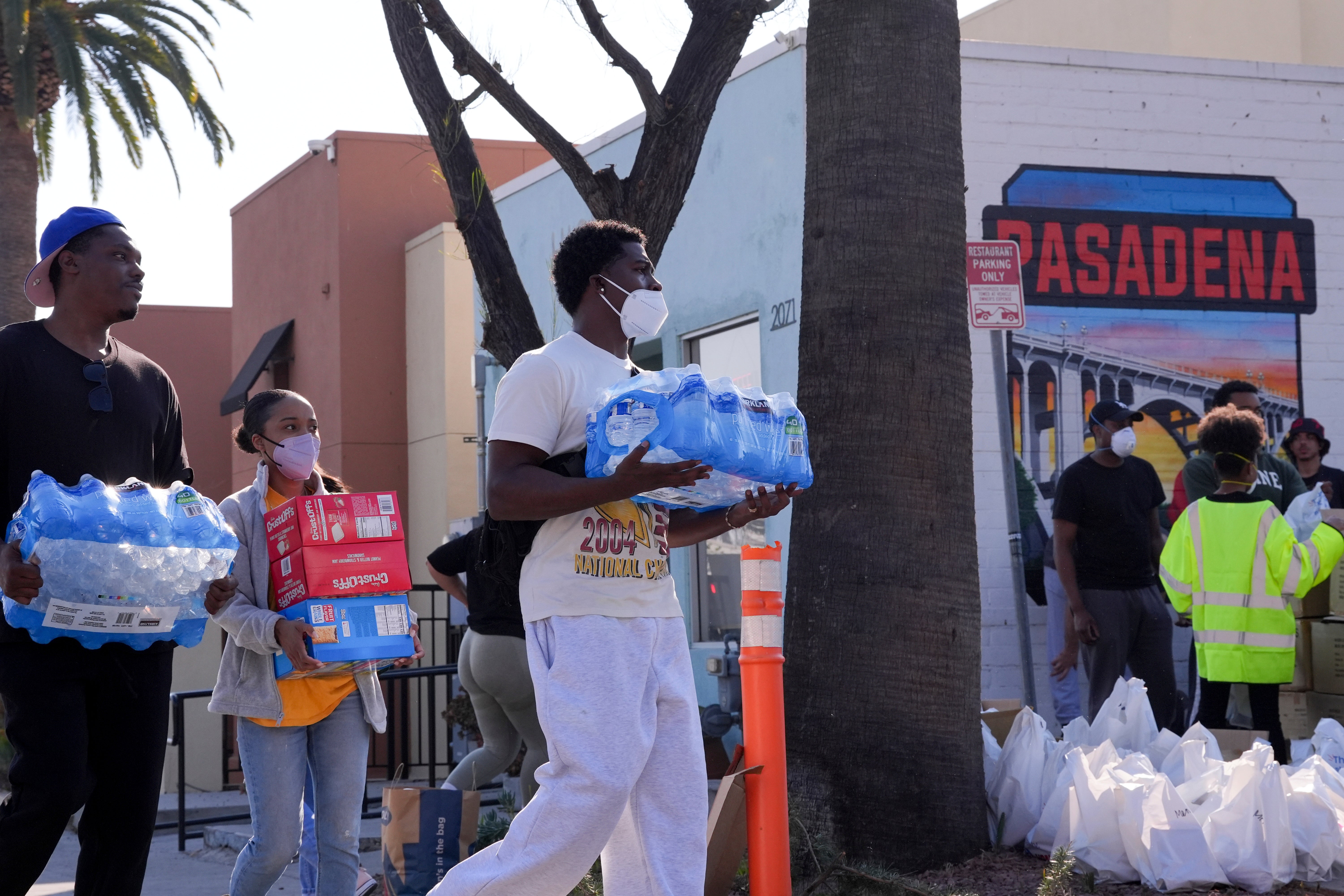 People pick up items at an aid center for those affected by wildfires on Saturday in Pasadena, California. The number of residents under evacuation orders has dropped markedly since last week