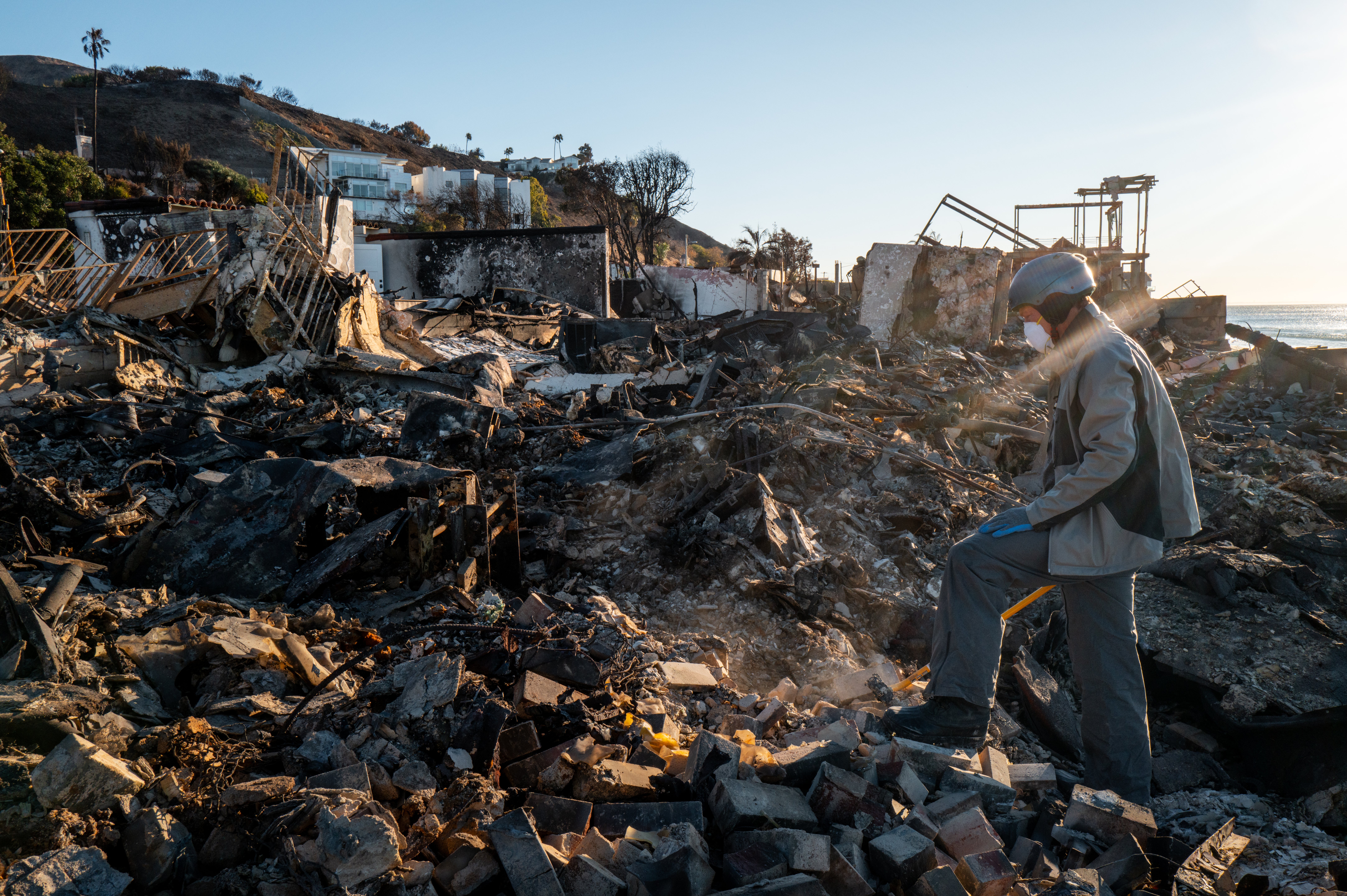 Patrick O'Neal sifts through his home after it was destroyed by the Palisades Fire on Monday in Malibu, California. More than 425 homes have been destroyed there, according to the city’s government