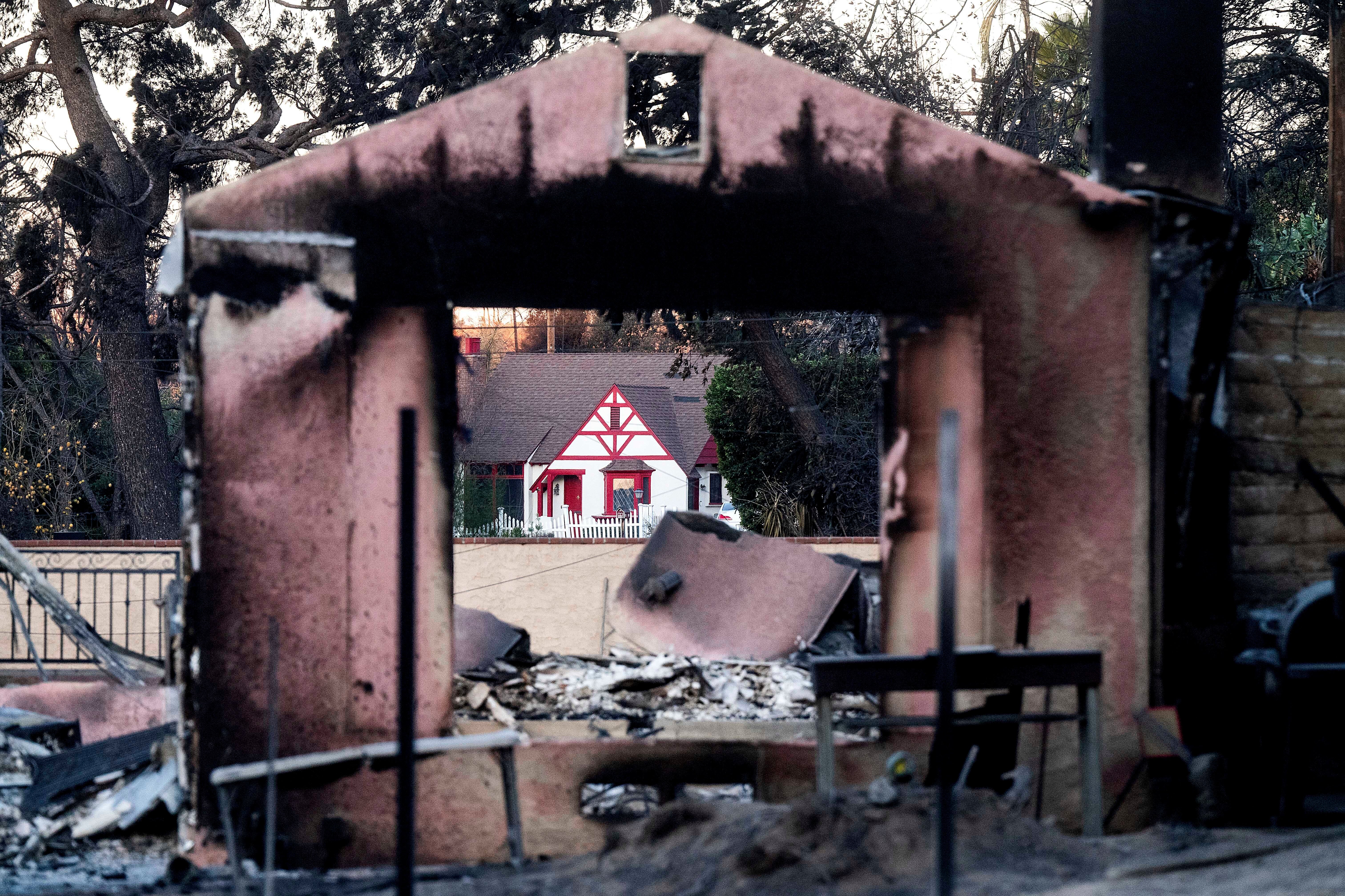 A home destroyed by the Eaton Fire stands in front of another that survived in Altadena, California on Monday. More than 12,000 structures have burned in the recent fires