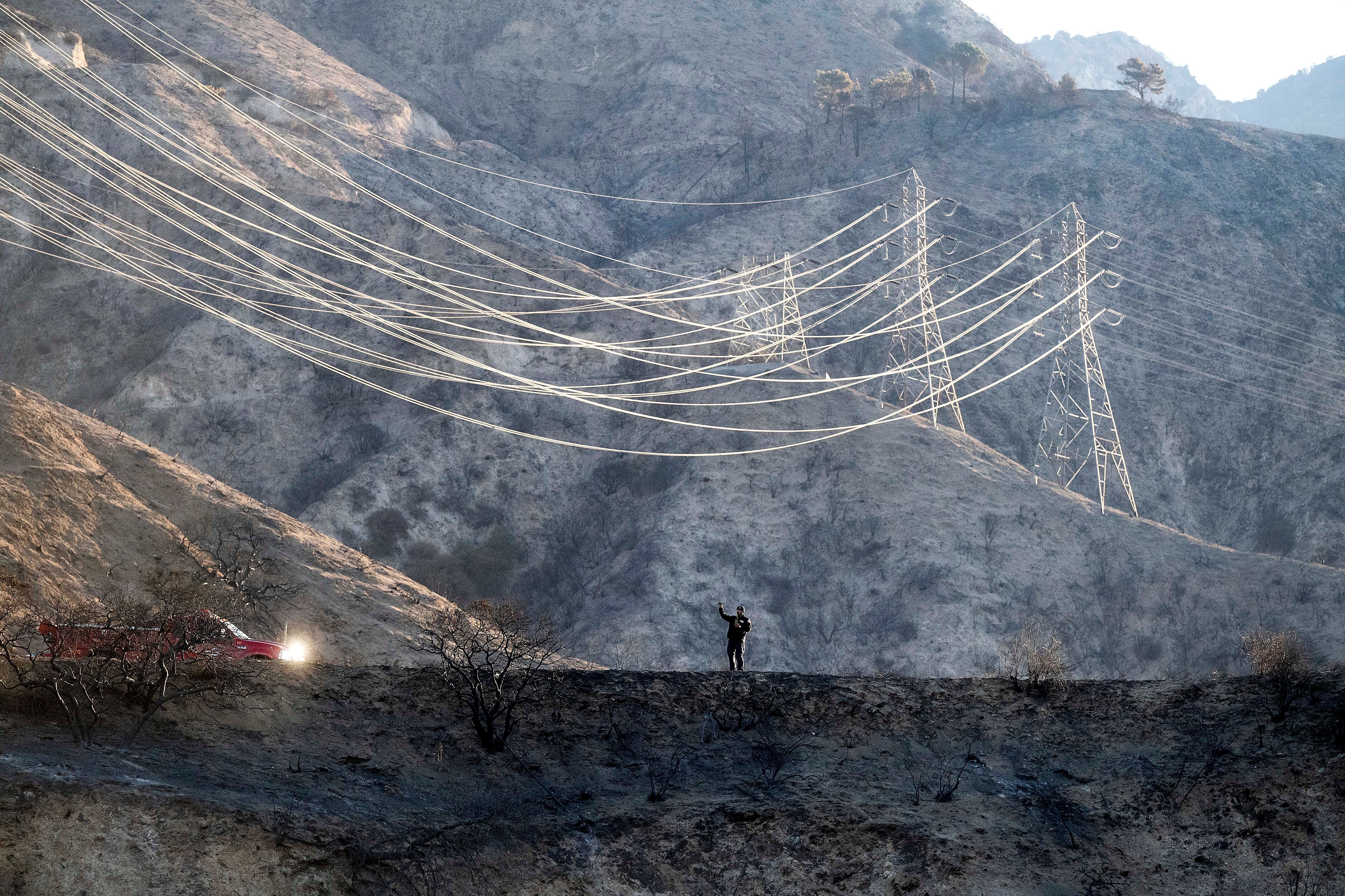 A firefighter takes weather readings while standing on a scorched ridgetop above the Eaton Fire on in California’s Angeles National Forest. Forecasters warned that conditions would swiftly deteriorate by Tuesday