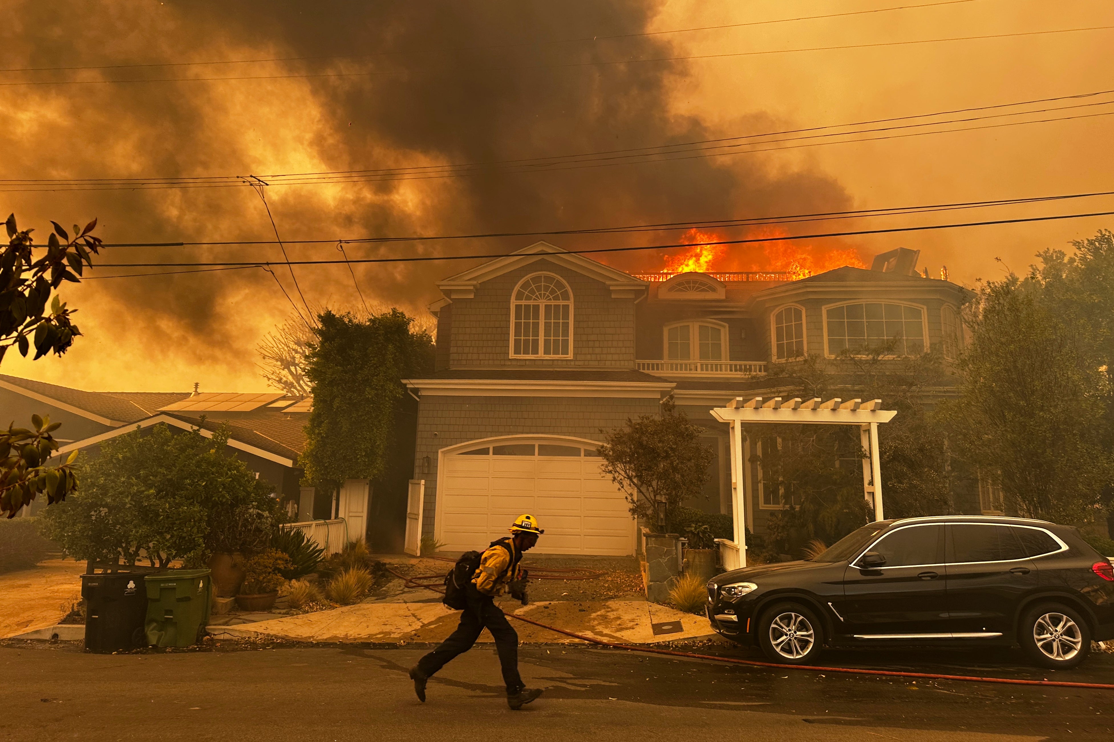 A residence burns as a firefighter battles the Palisades Fire in the Pacific Palisades neighborhood of Los Angeles Tuesday, Jan. 7, 2025.