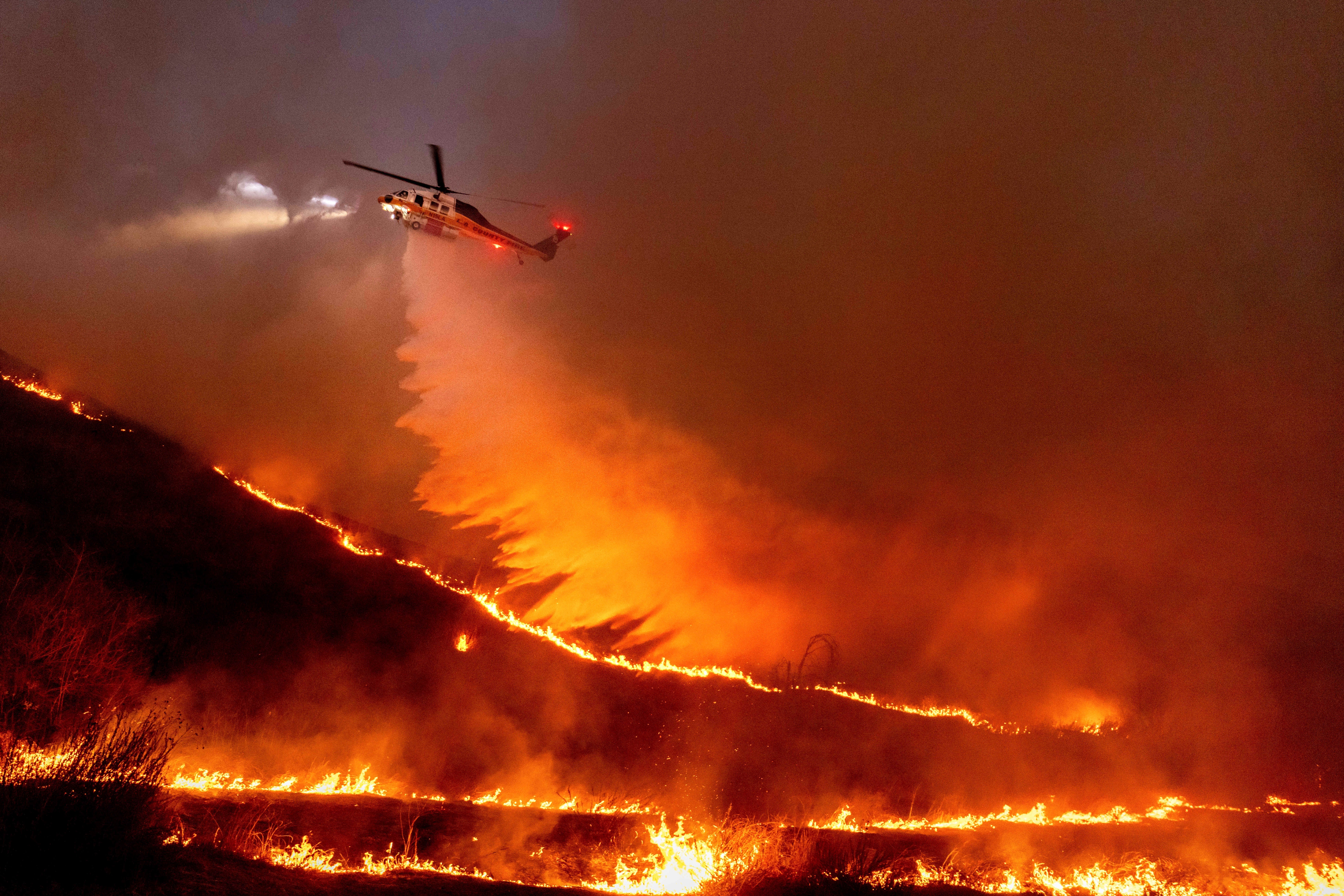 Water is dropped by helicopter on the Kenneth Fire in the West Hills section of Los Angeles on January 9