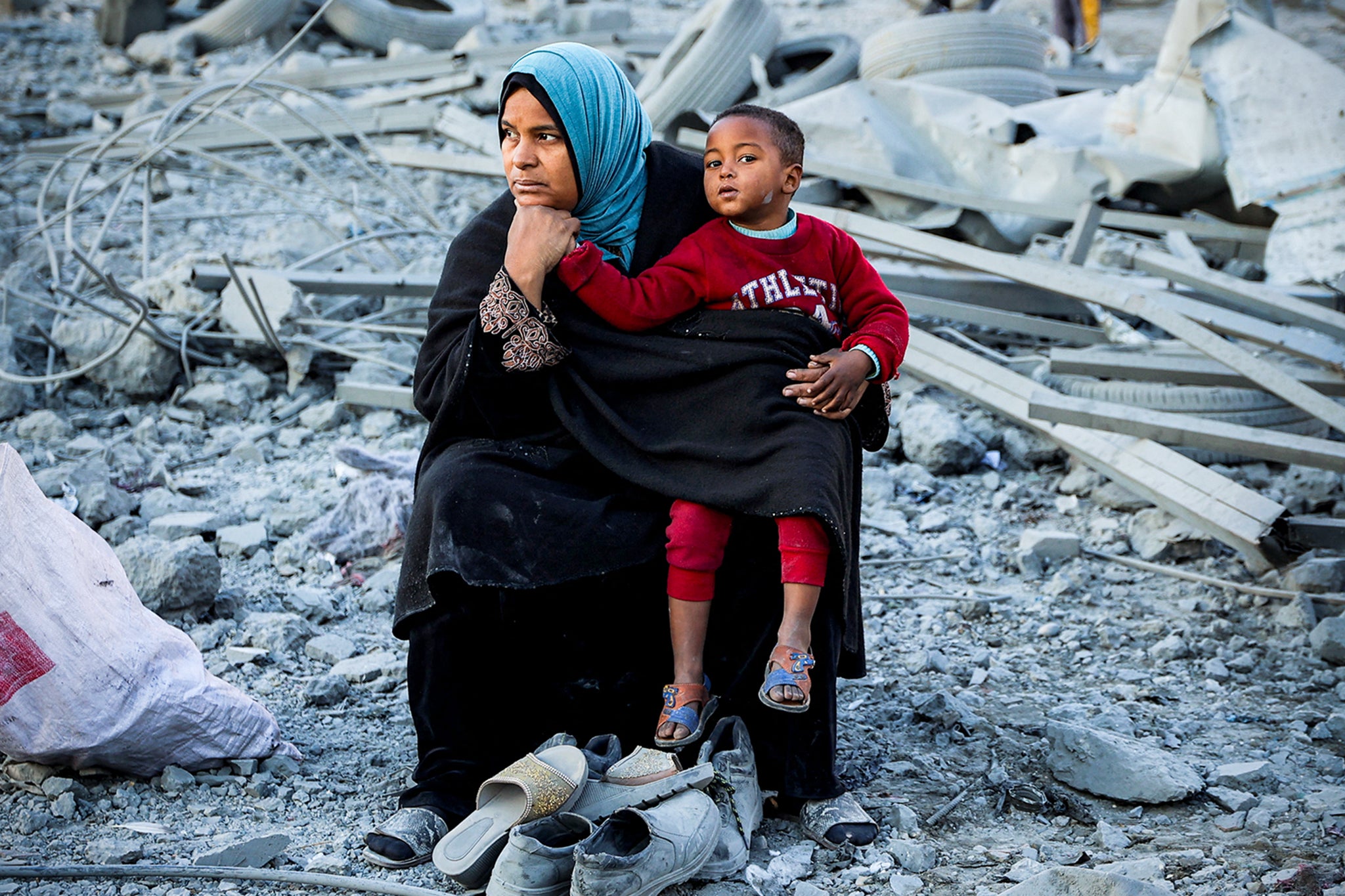 A woman and her child sit amid the rubble following the Israeli bombardment of Gaza City on 14 January