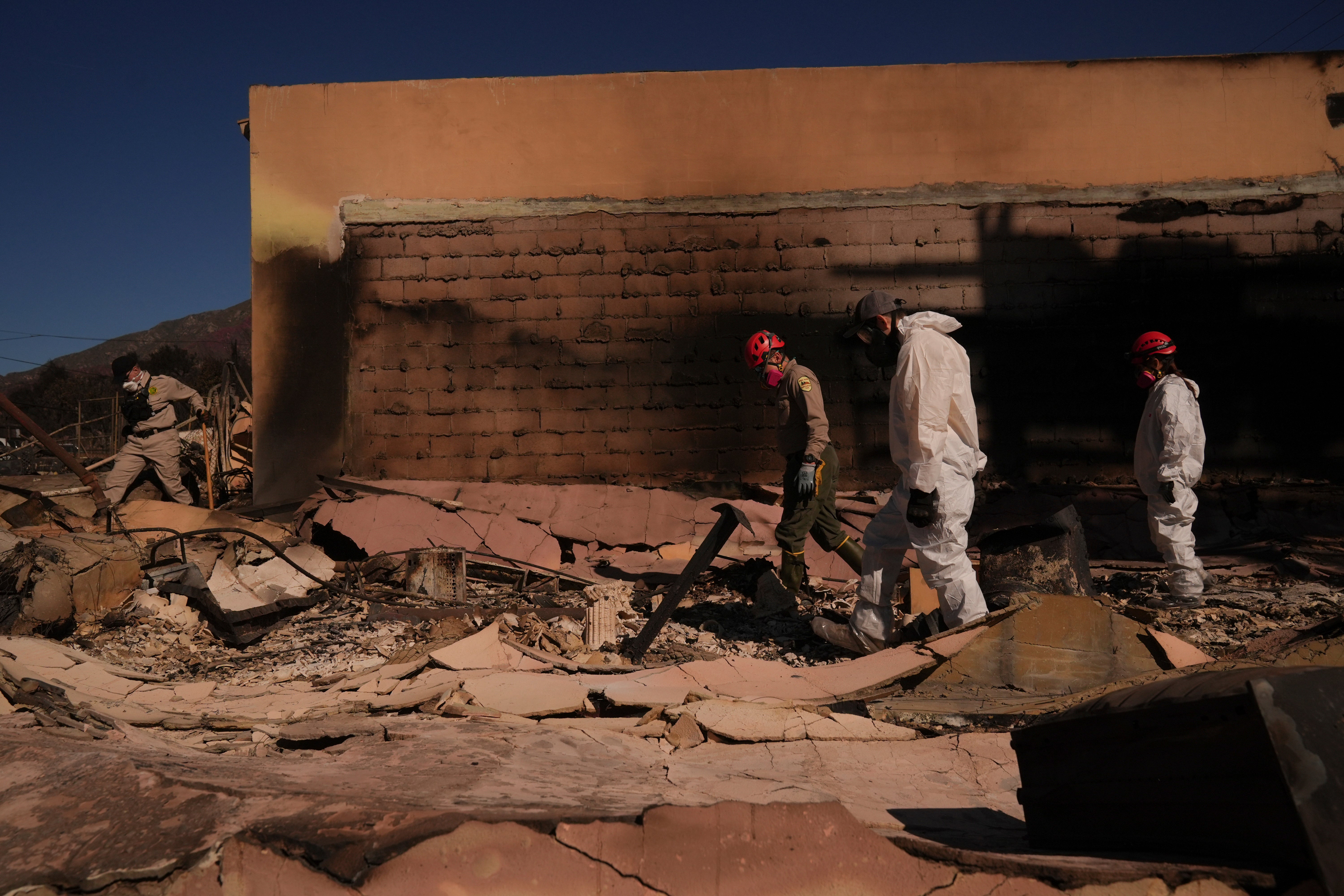 Search and rescue workers dig through the rubble left behind by the Eaton Fire, in Altadena, California, on Tuesday. The fire is still raging over more than 14,000 acres