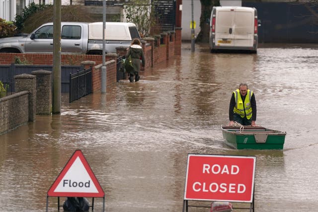 <p>A warden pushes a boat in floodwater after Storm Darragh hit the UK in December 2024</p>