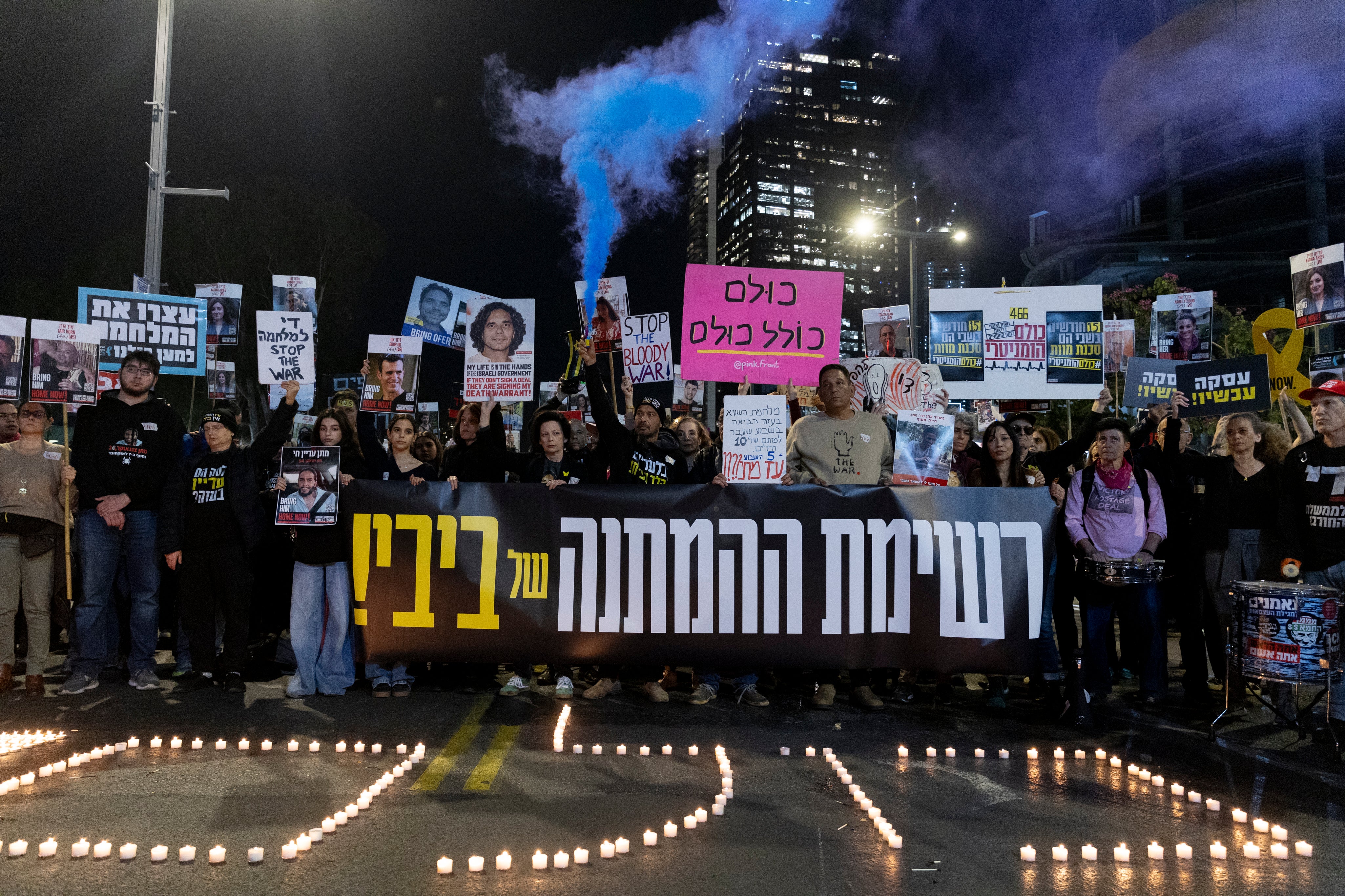 Protesters hold photos of hostages and a smoke torch during a demonstration calling for the return of hostages held by Hamas