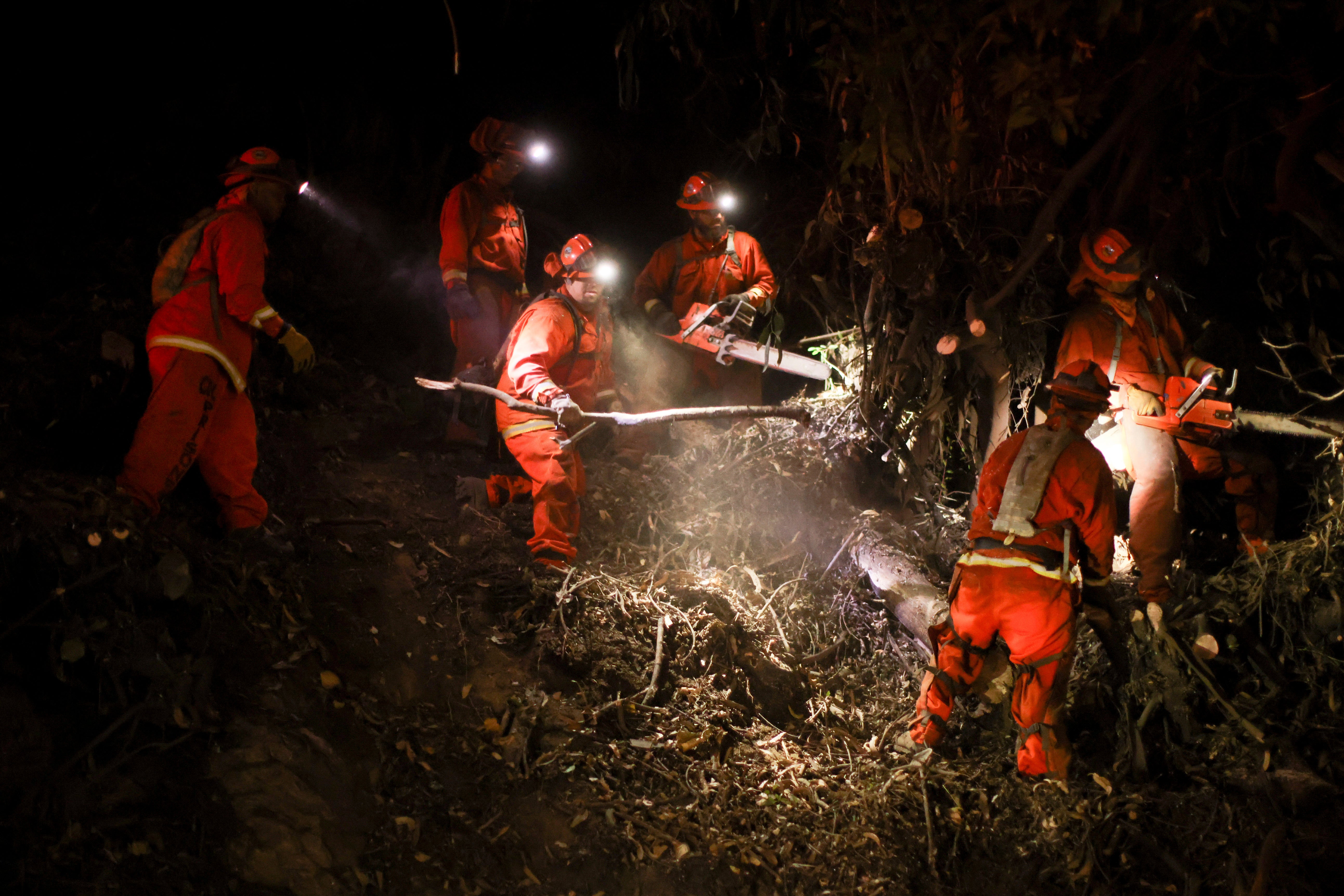 A California Department of Corrections hand crew works containment lines ahead of the Palisades Fire on Tuesday in Santa Monica, California. Winds were expected to ease by midday on Wednesday