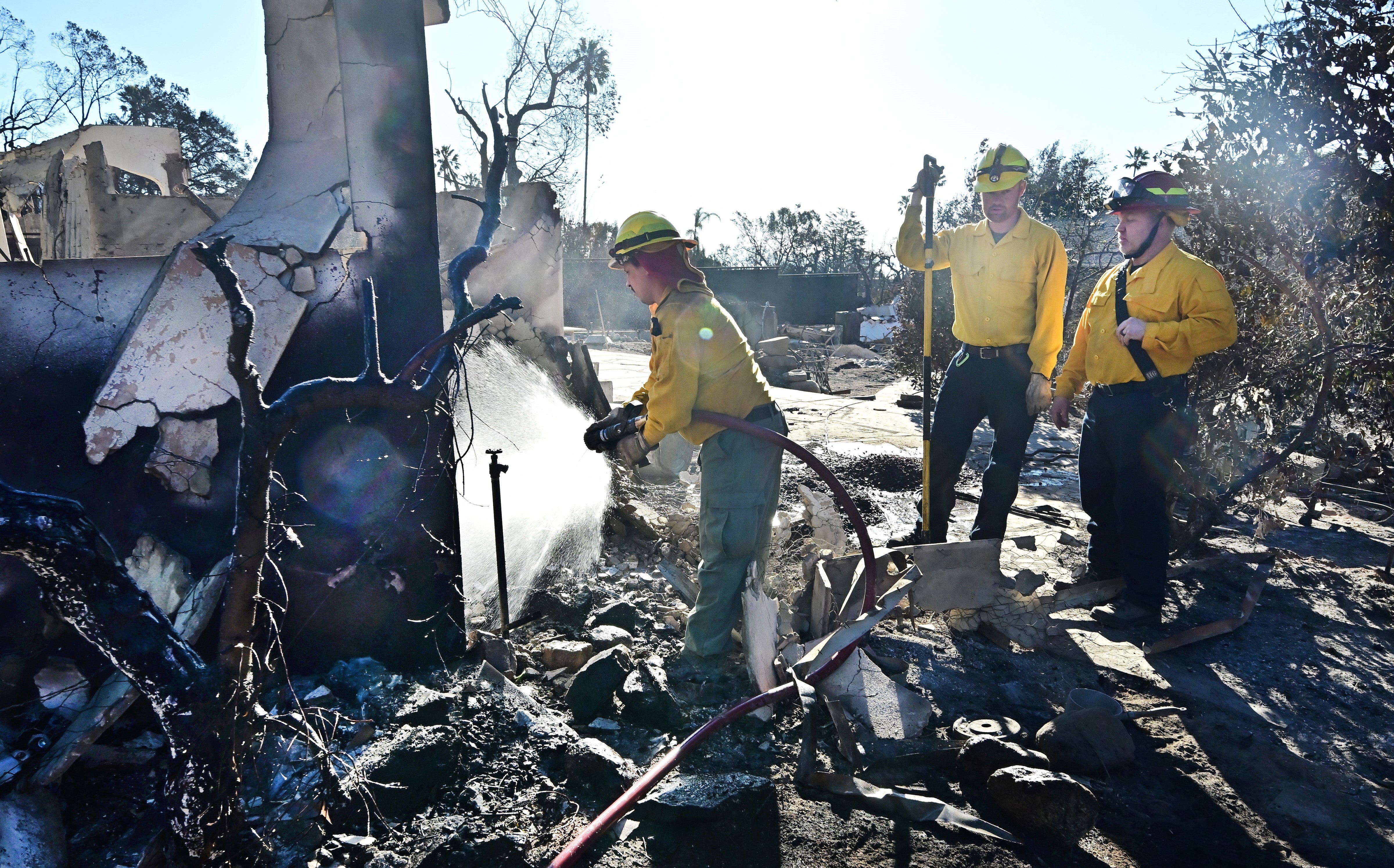 <p>Firefighters from Idaho spray down the rubble of homes demolished by the Eaton Fire in Altadena, on Wednesday </p>