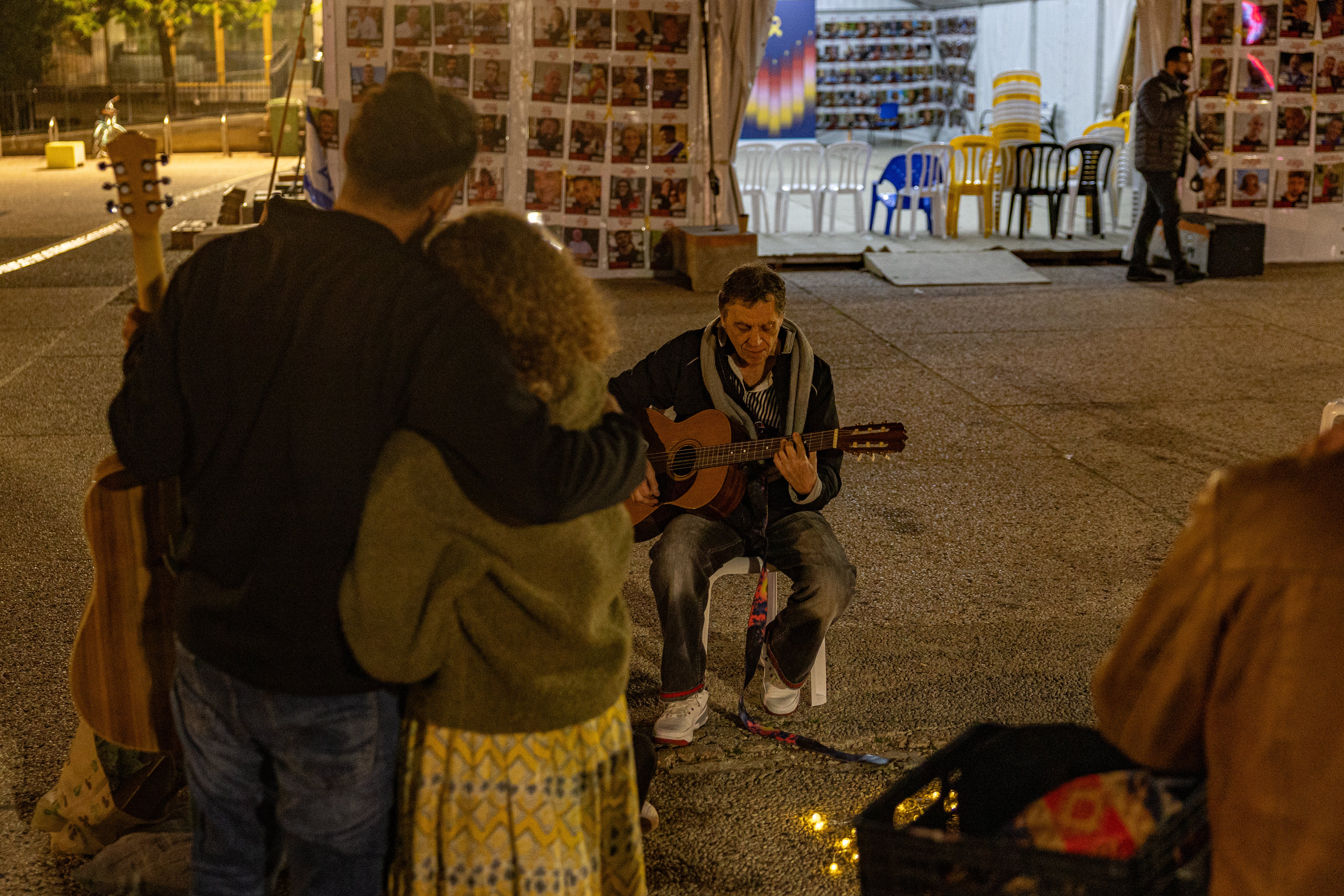 A man plays his guitar in Tel Aviv as people watch on