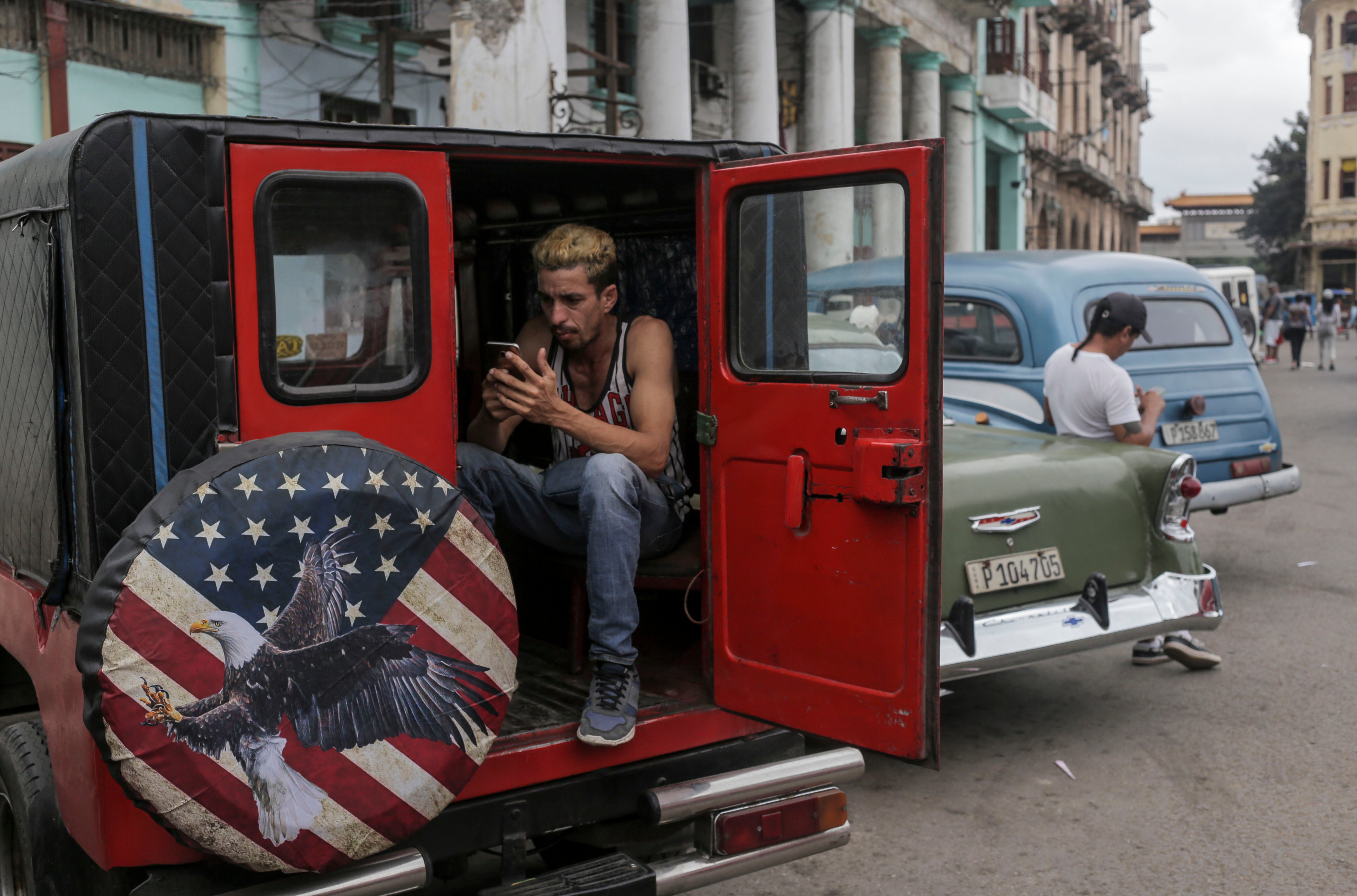 A person uses a cellphone inside a private cab in Havana, Cuba, Wednesday, Jan. 15, 2025