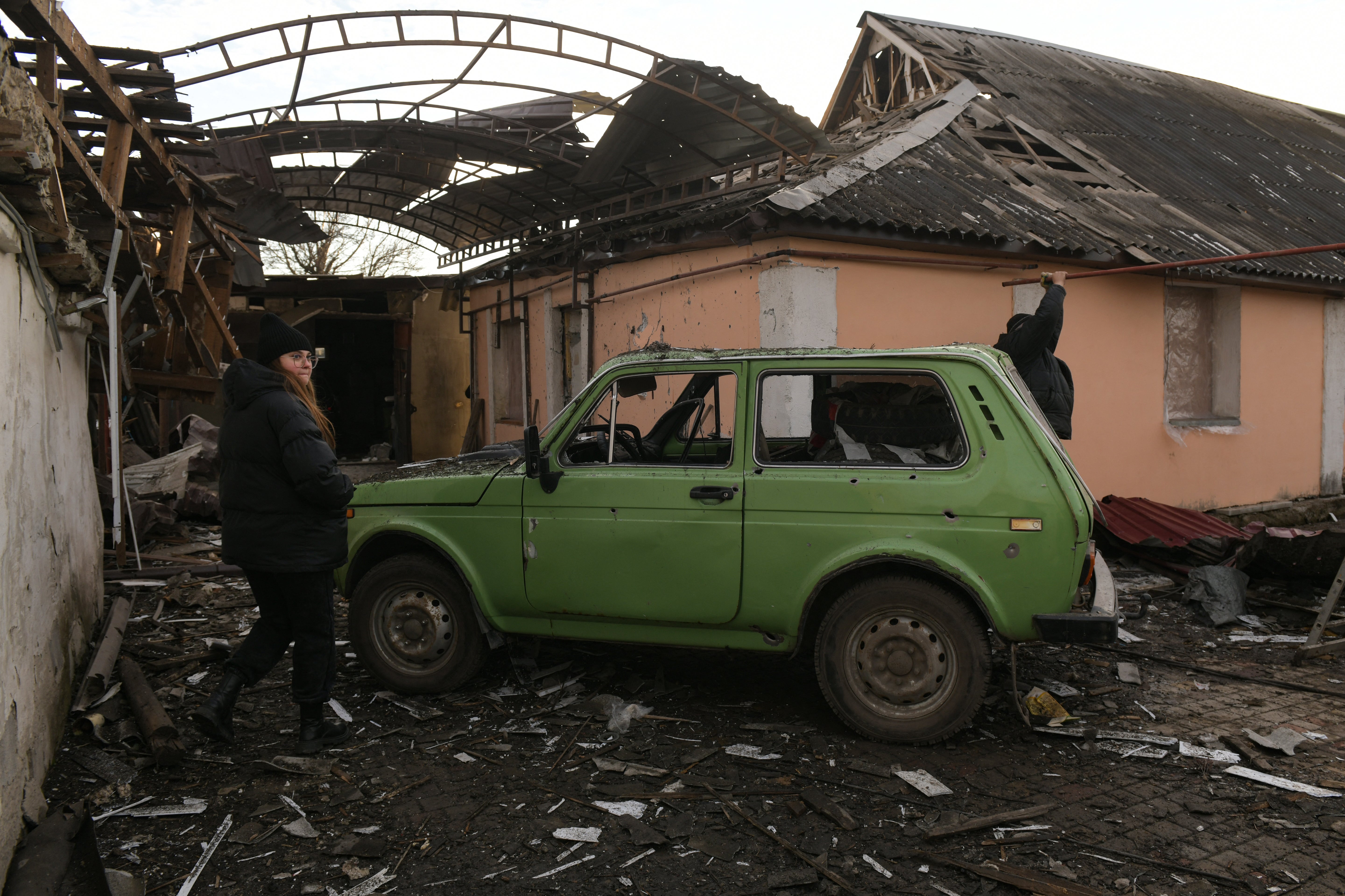 A woman stands in the yard of a destroyed house hit by shelling in Makiivka (Makeyevka) in the Donetsk region