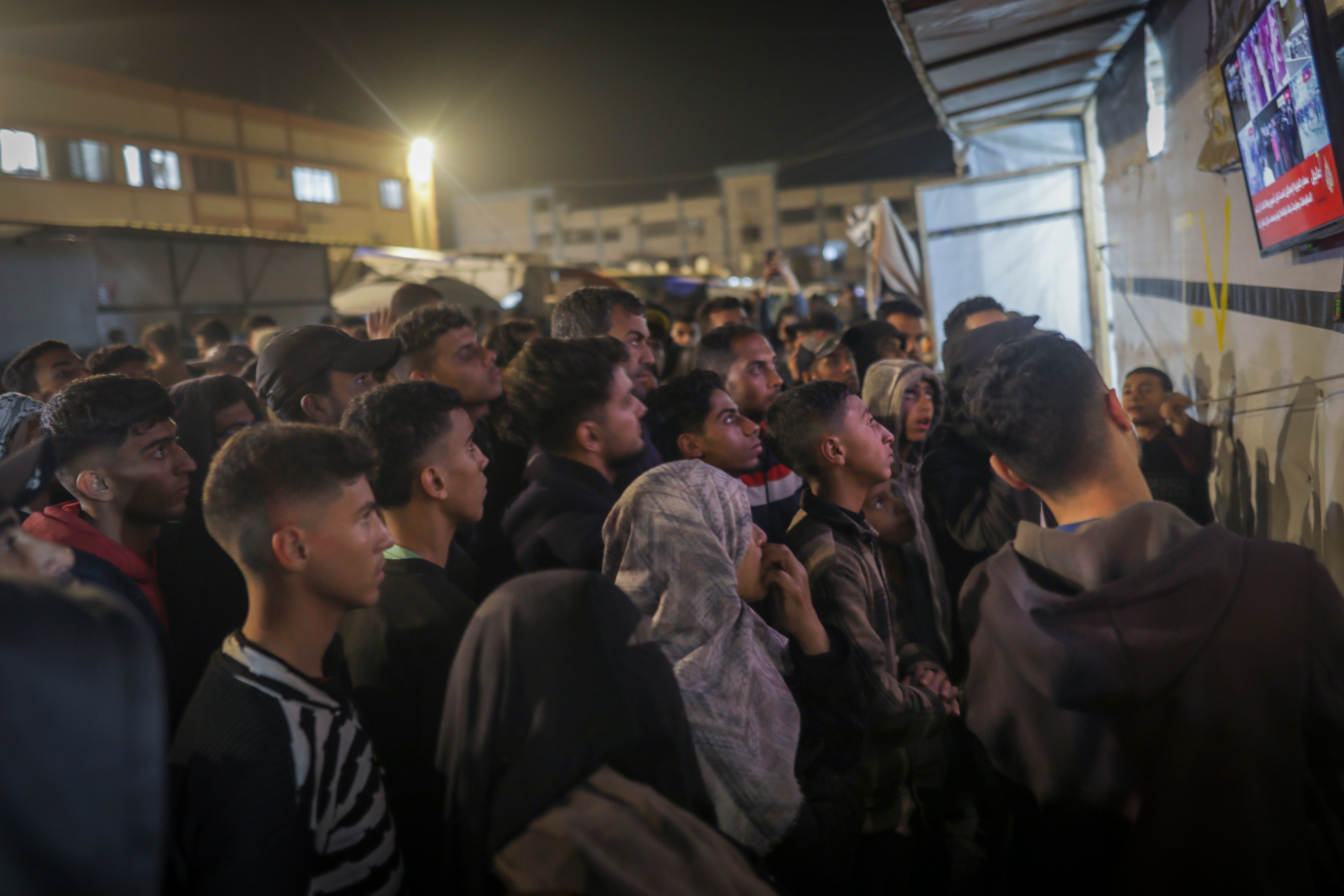 Palestinians watch TV as they await the announcement of a ceasefire deal between Hamas and Israel in Khan Younis