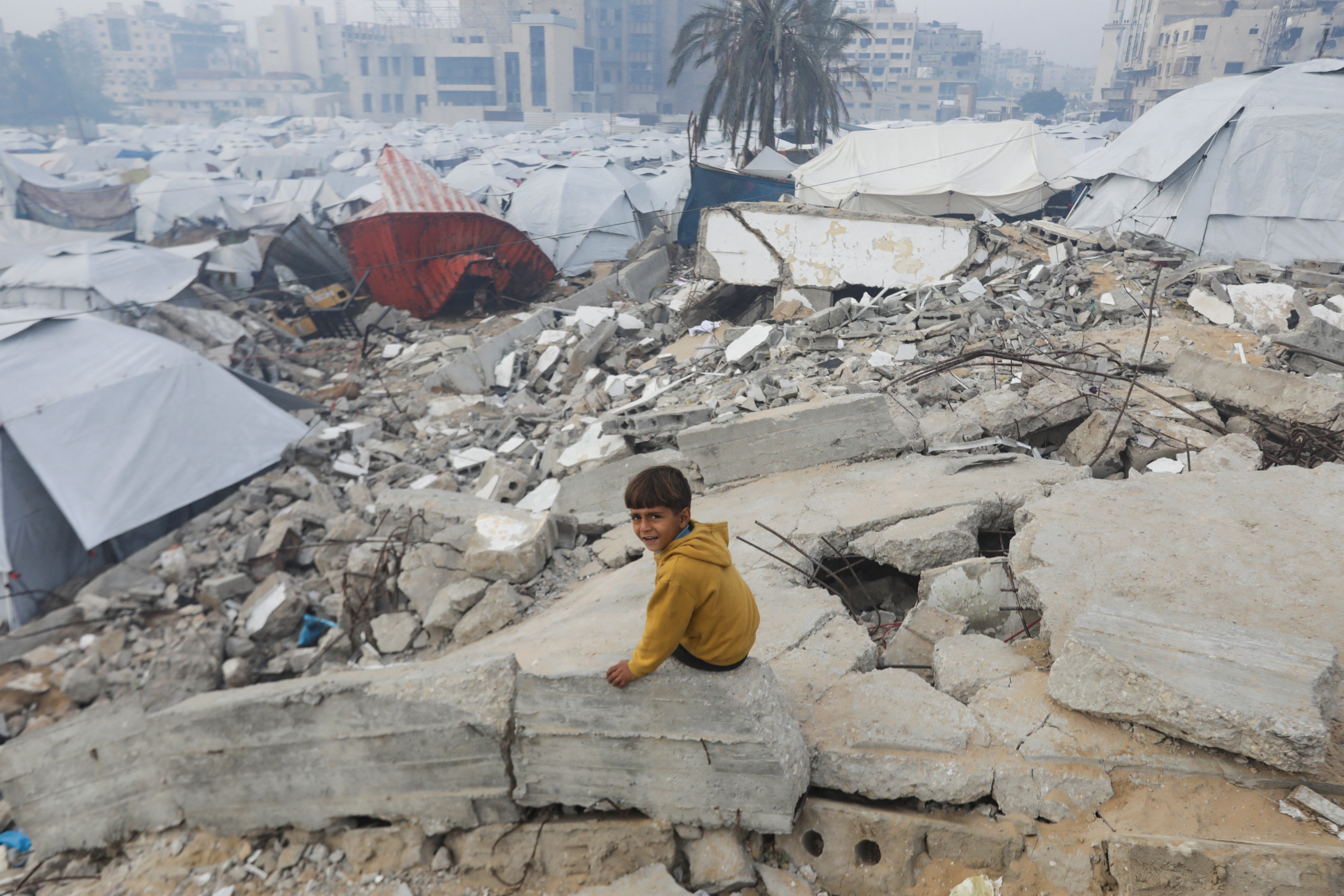 A Palestinian child sits amid the rubble of buildings destroyed in Gaza City