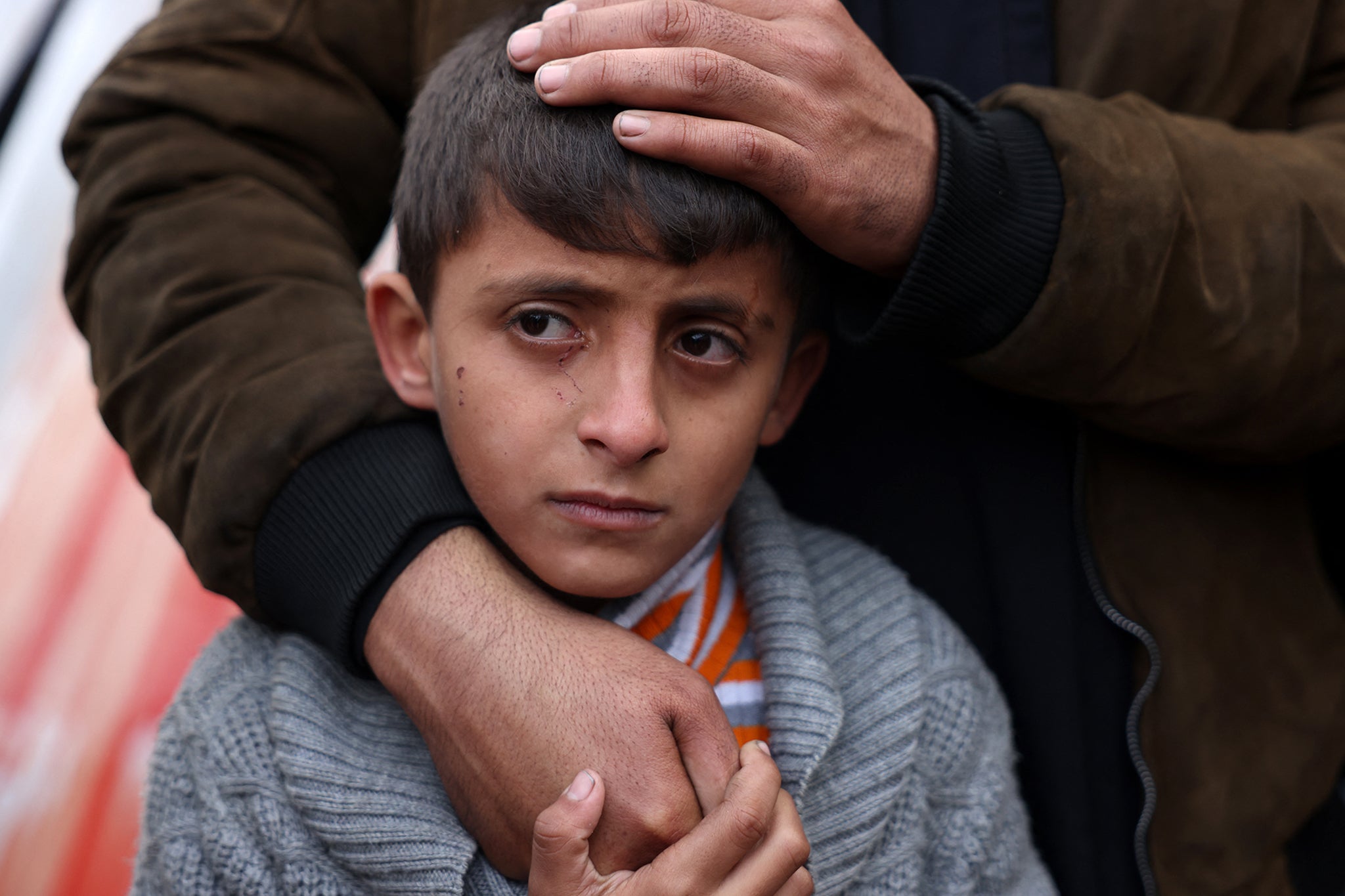 A Palestinian boy is comforted as he mourns the death of a loved one killed an Israeli strike the previous night, outside Nasser Hospital in Khan Younis, in the southern Gaza Strip