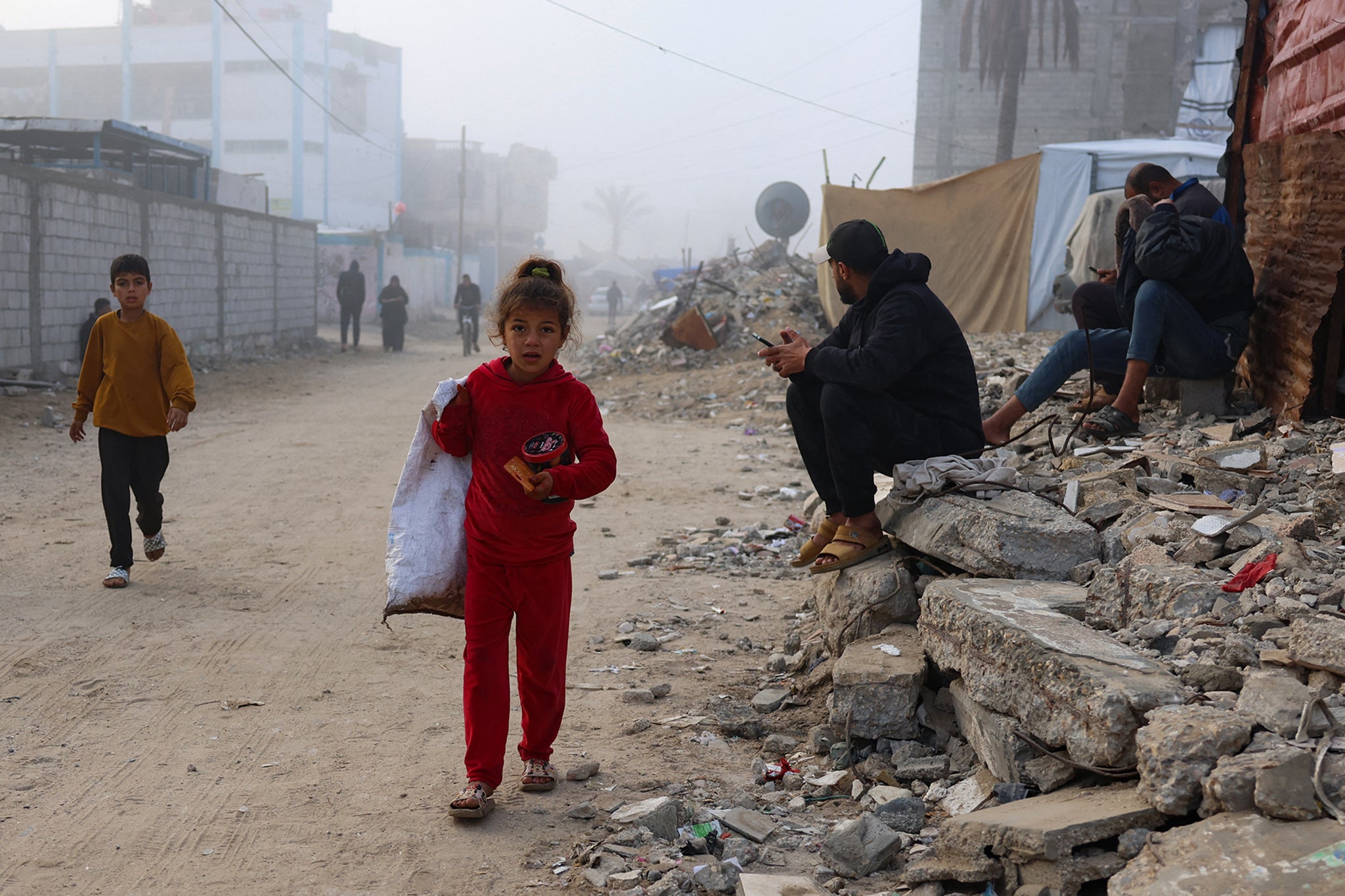 A young Palestinian girl walks along a street on a misty morning in Khan Younis, Gaza