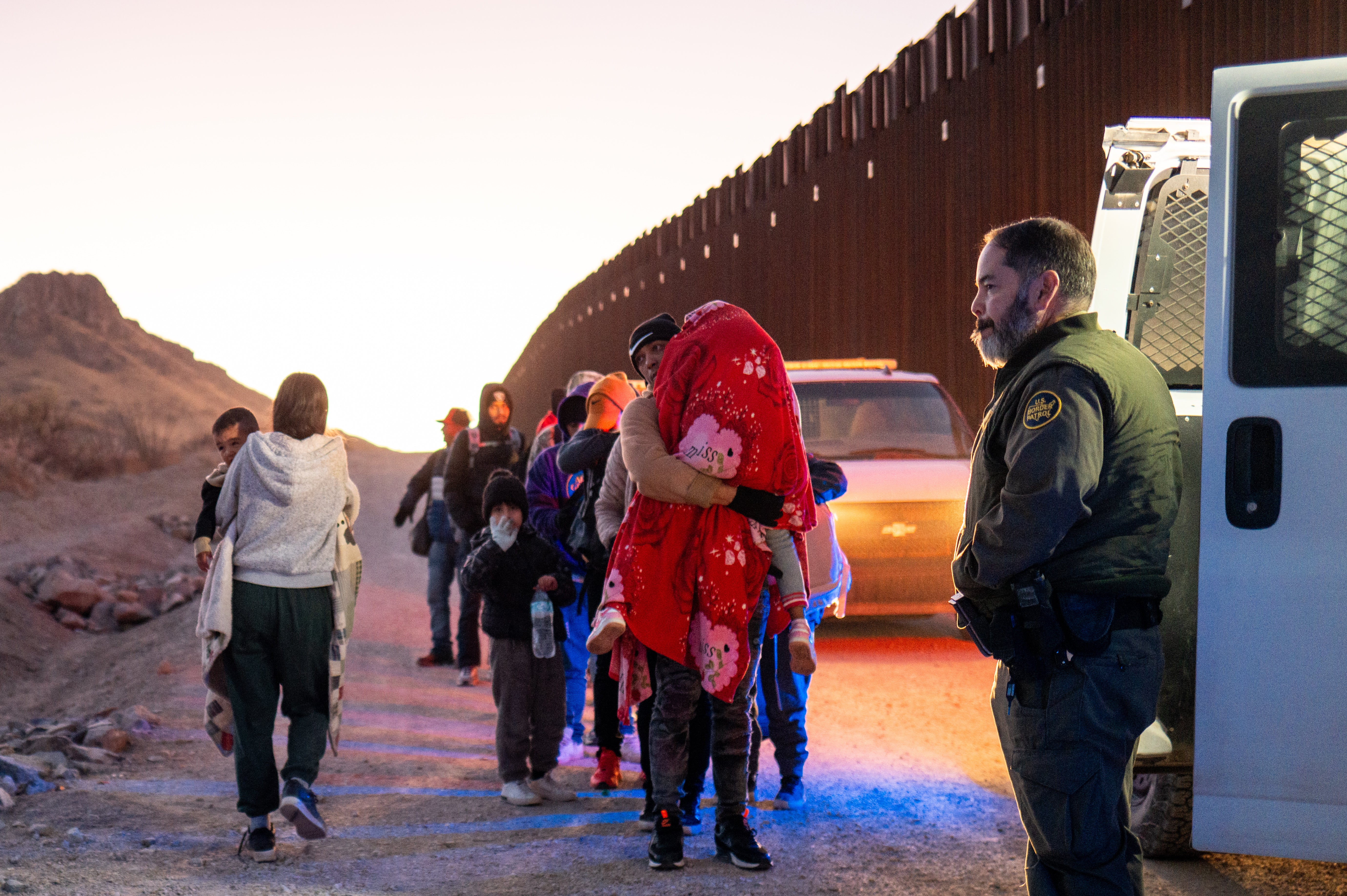 Migrants turn themselves in to U.S. Customs and Border Patrol officers after crossing over a section of border wall on January 5.