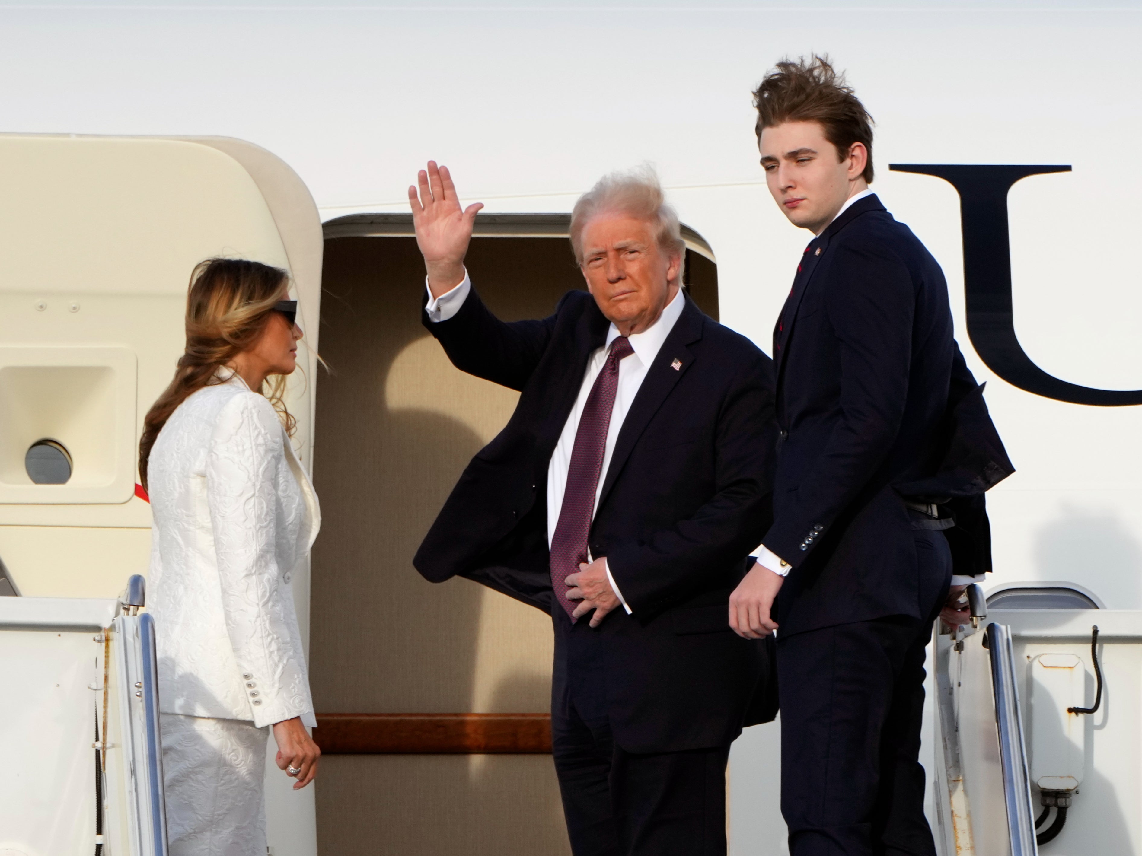 President-elect Donald Trump, standing with Melania and Barron Trump, waves as they board an Air Force Special Mission airplane at Palm Beach International Airport