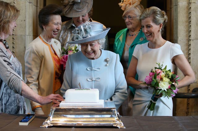 <p>The then-Countess of Wessex and the Princess Royal look on as the Queen cuts a Women’s Institute 100th anniversary cake in 2015</p>